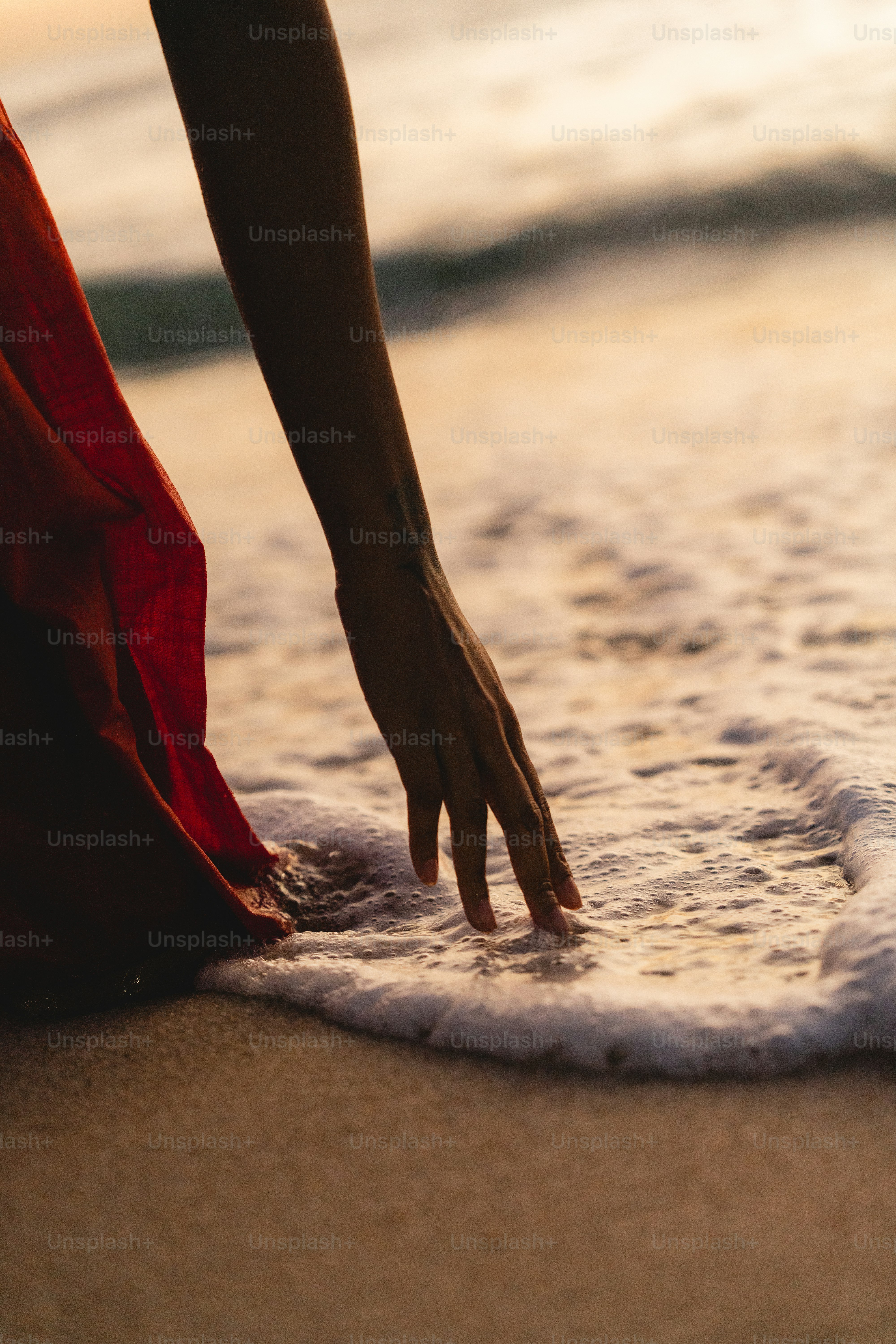 A person reaching into the water at the beach