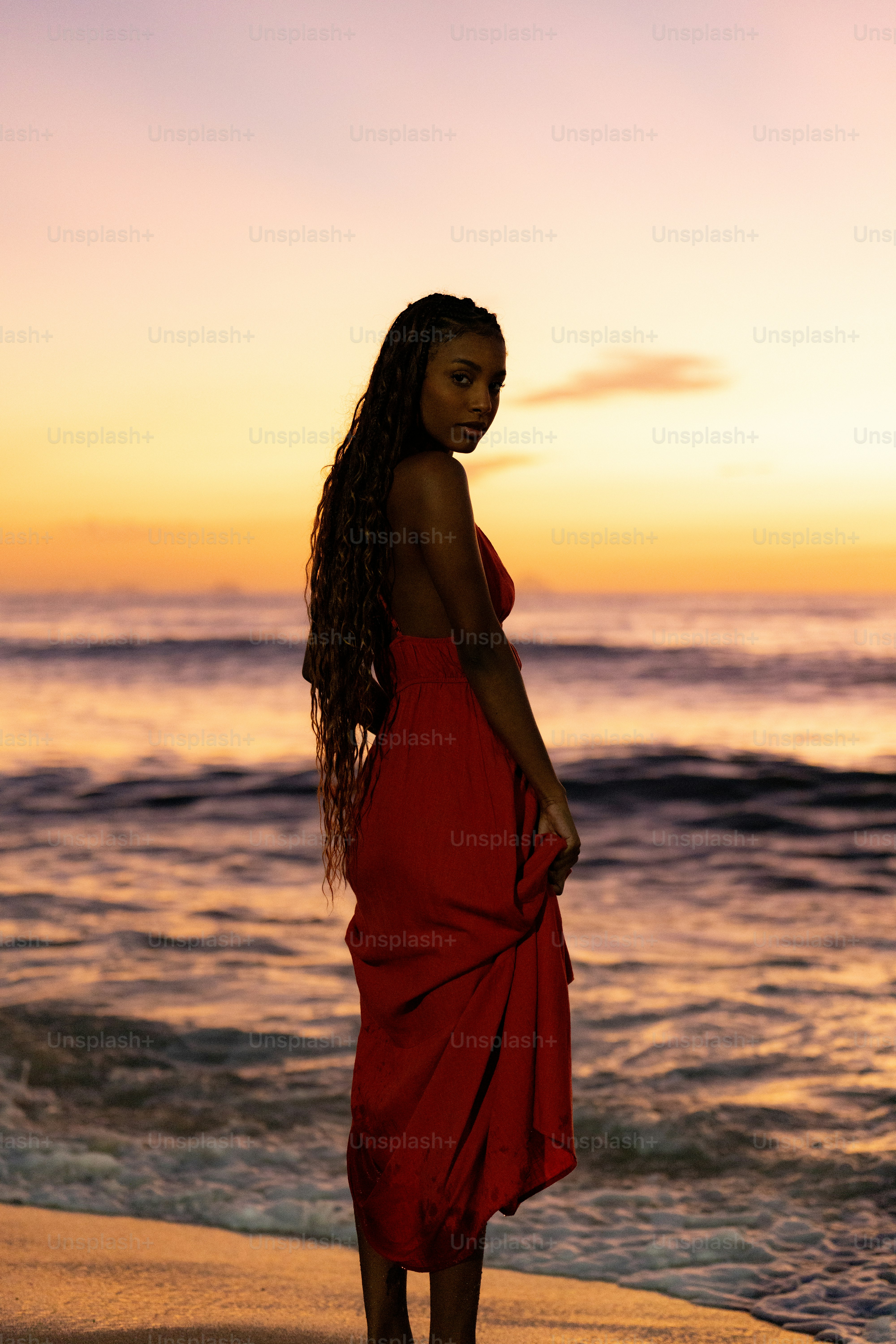 Uma mulher em um vestido vermelho em pé em uma praia