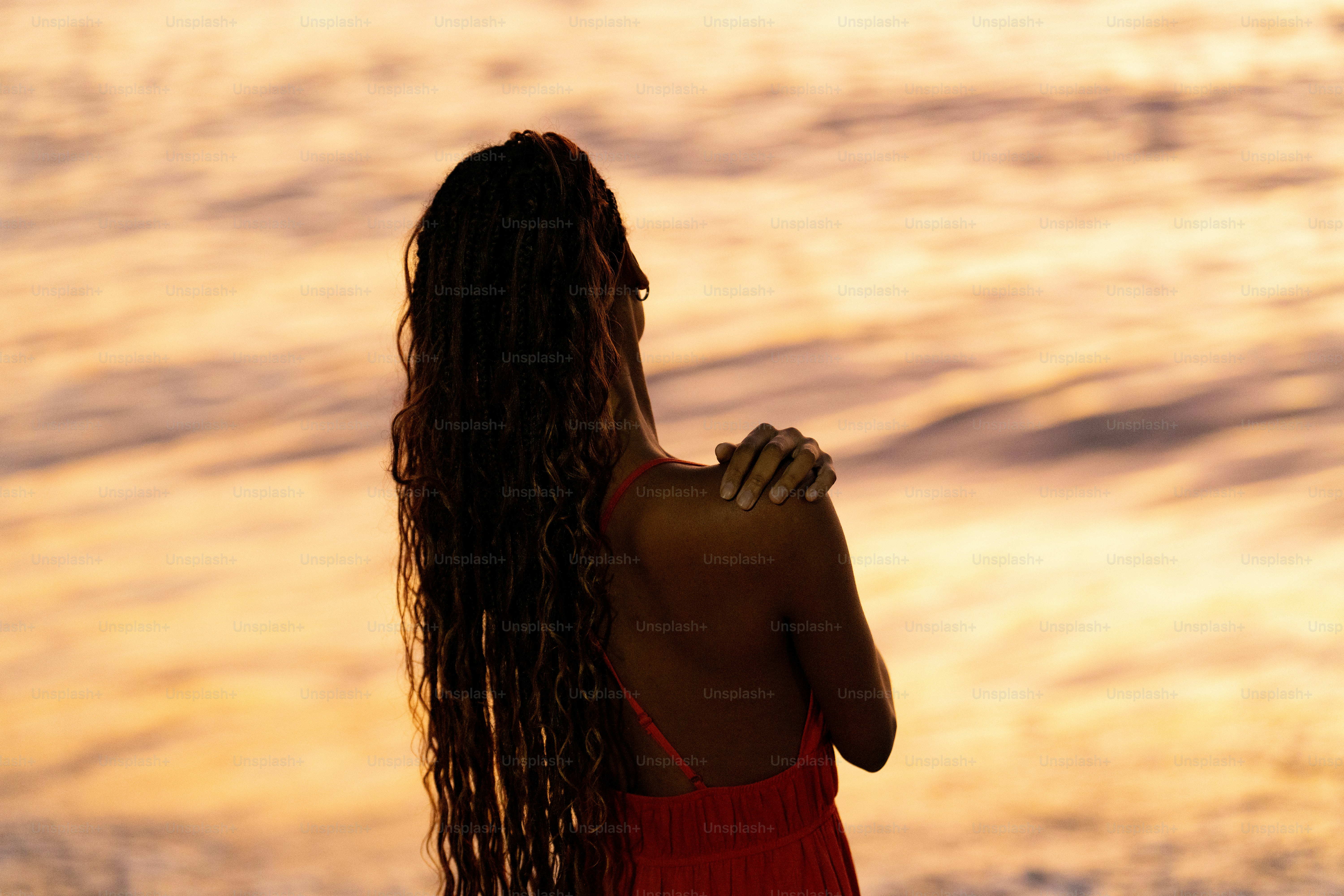 Uma mulher em um vestido vermelho em pé em uma praia