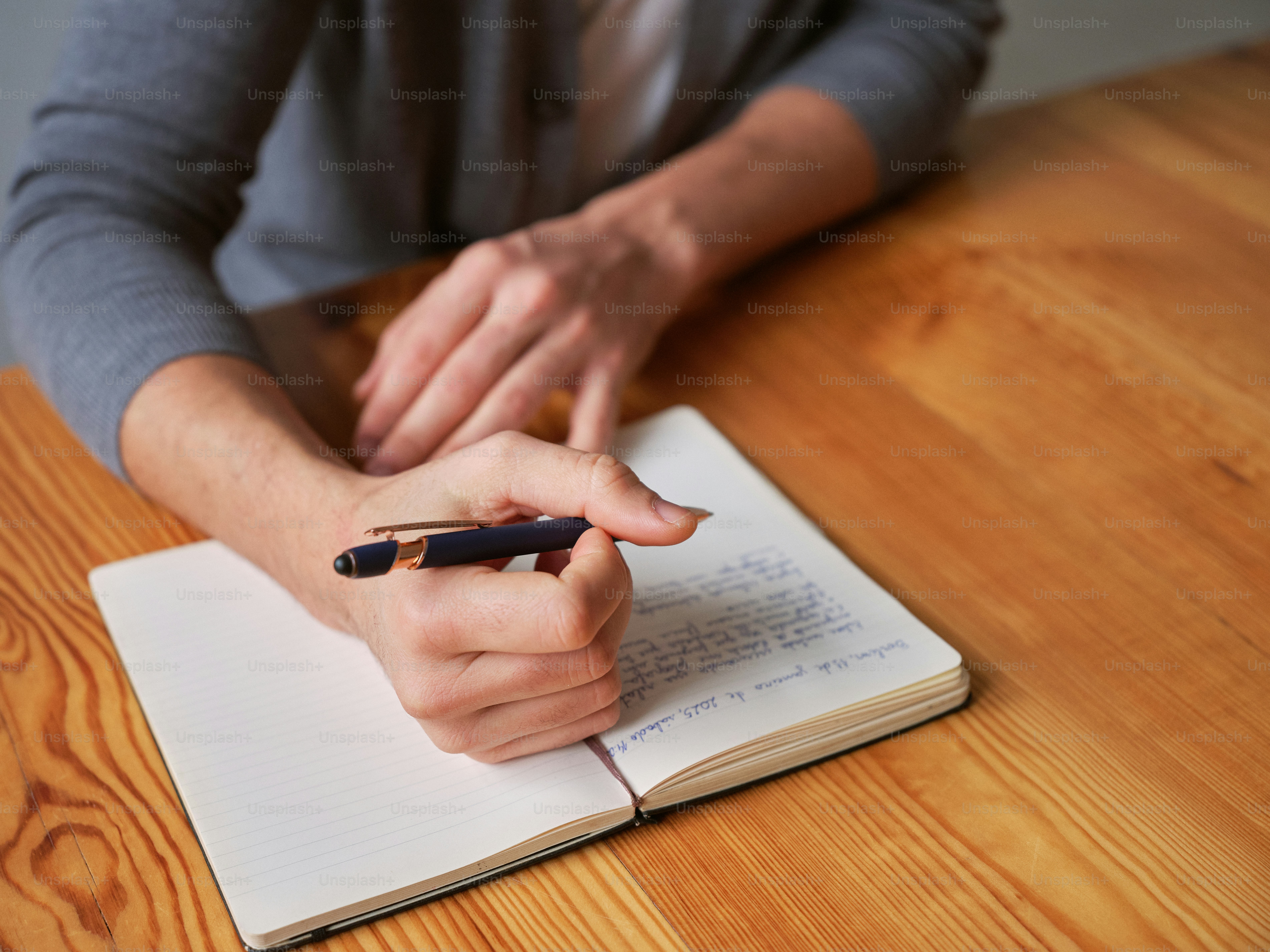 A person sitting at a table writing on a notebook