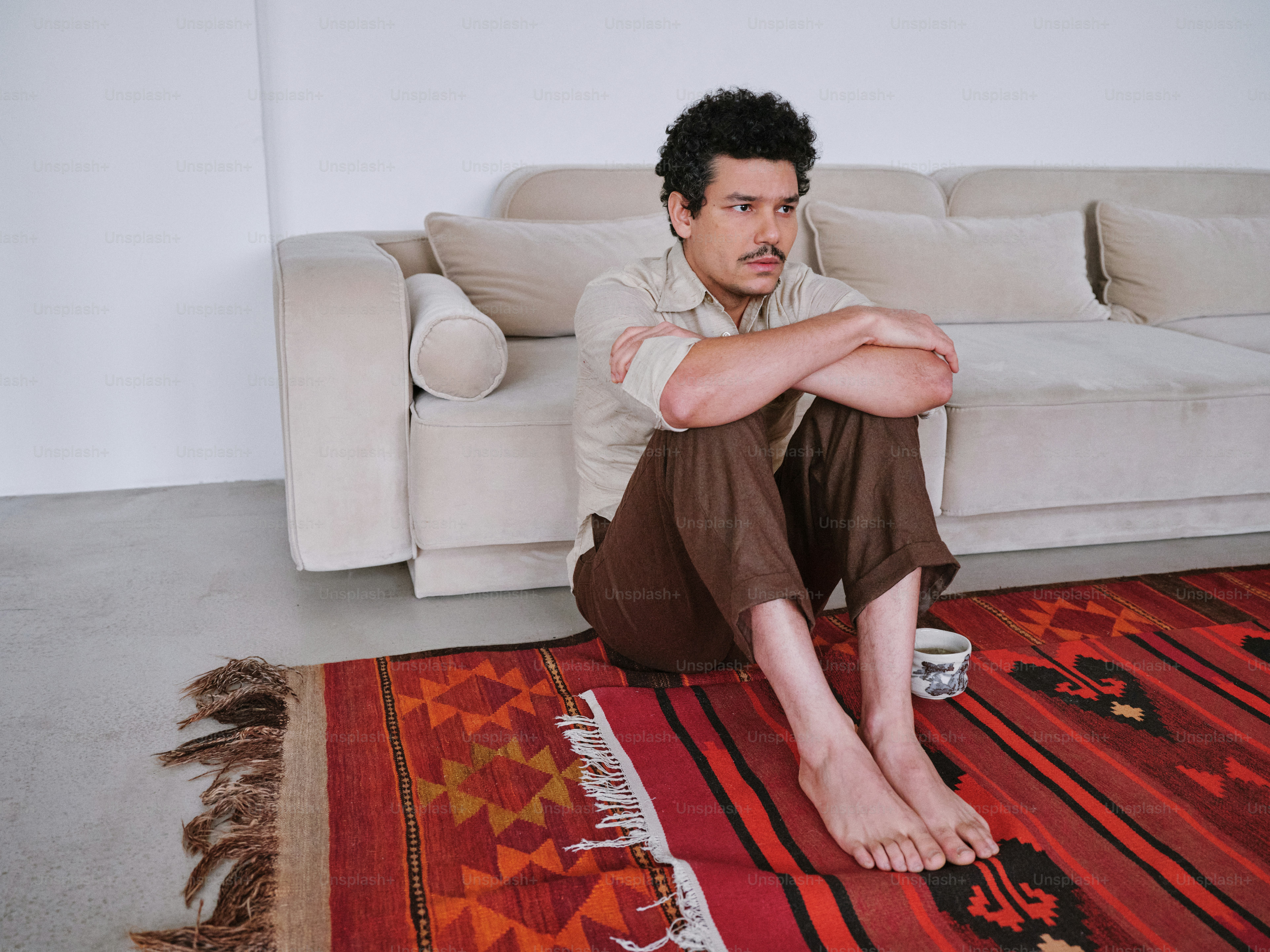 A man sitting on a rug in front of a couch