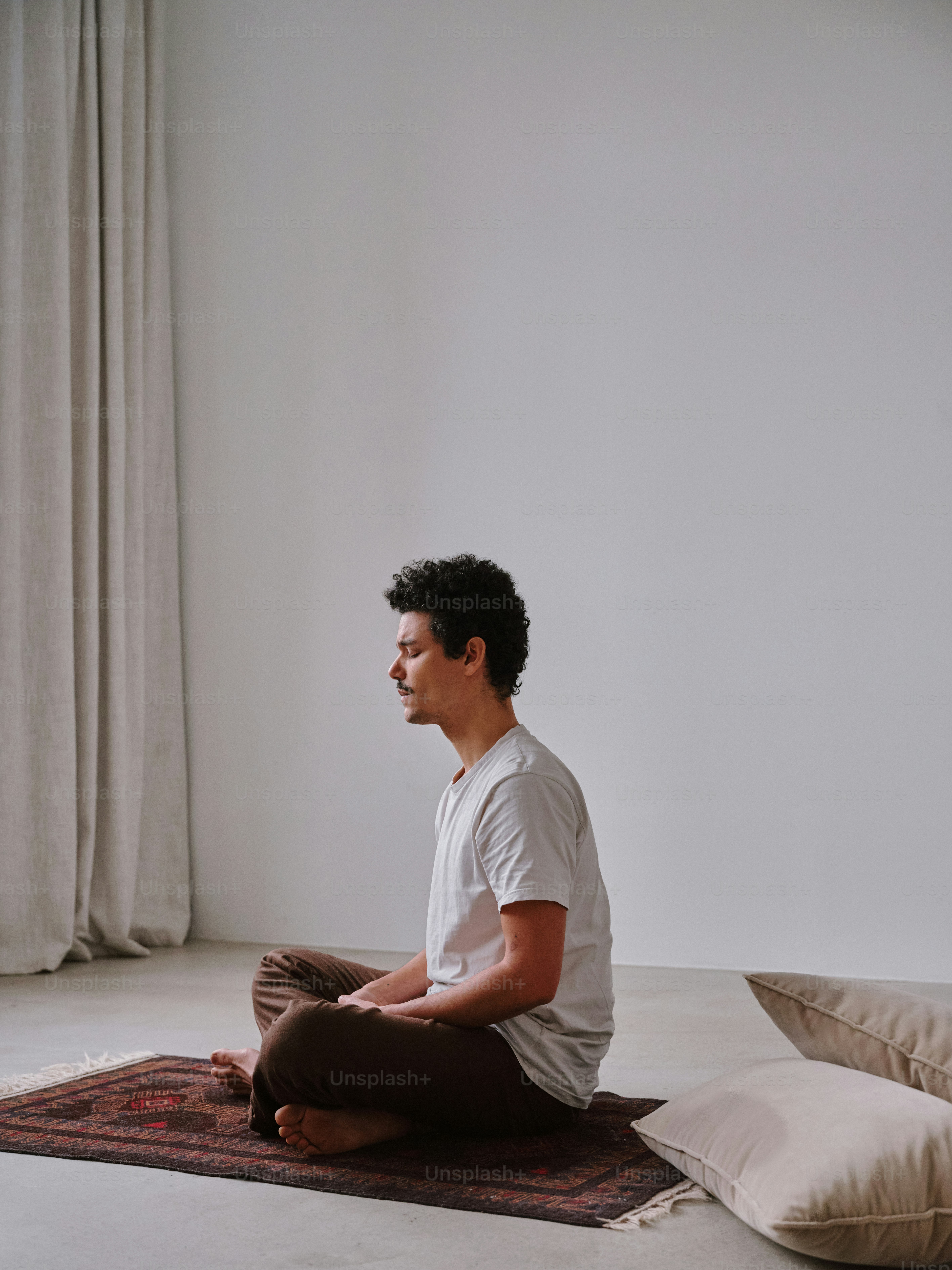 A man sitting on a rug in front of a window