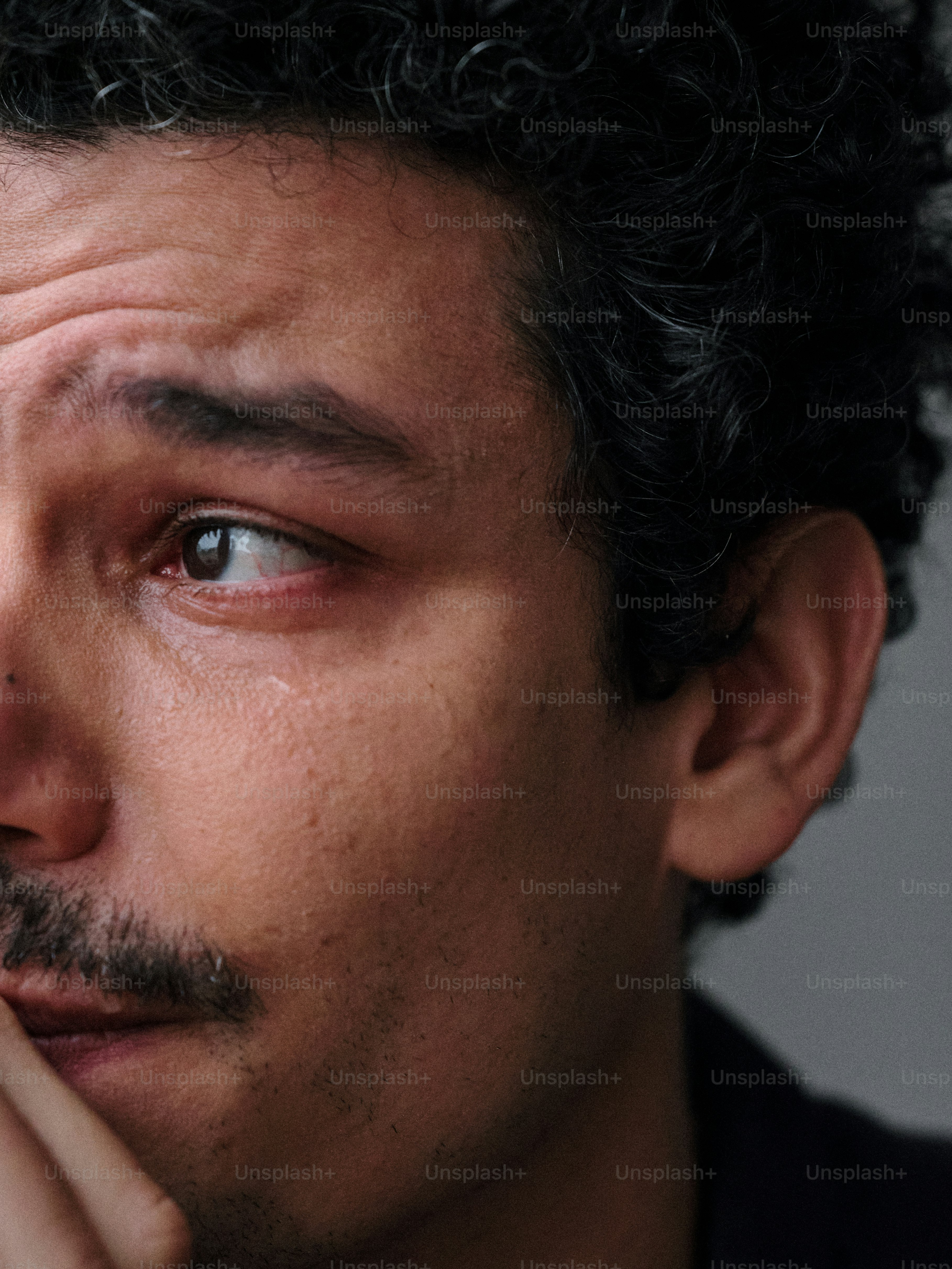A close up of a person holding his hand to his face