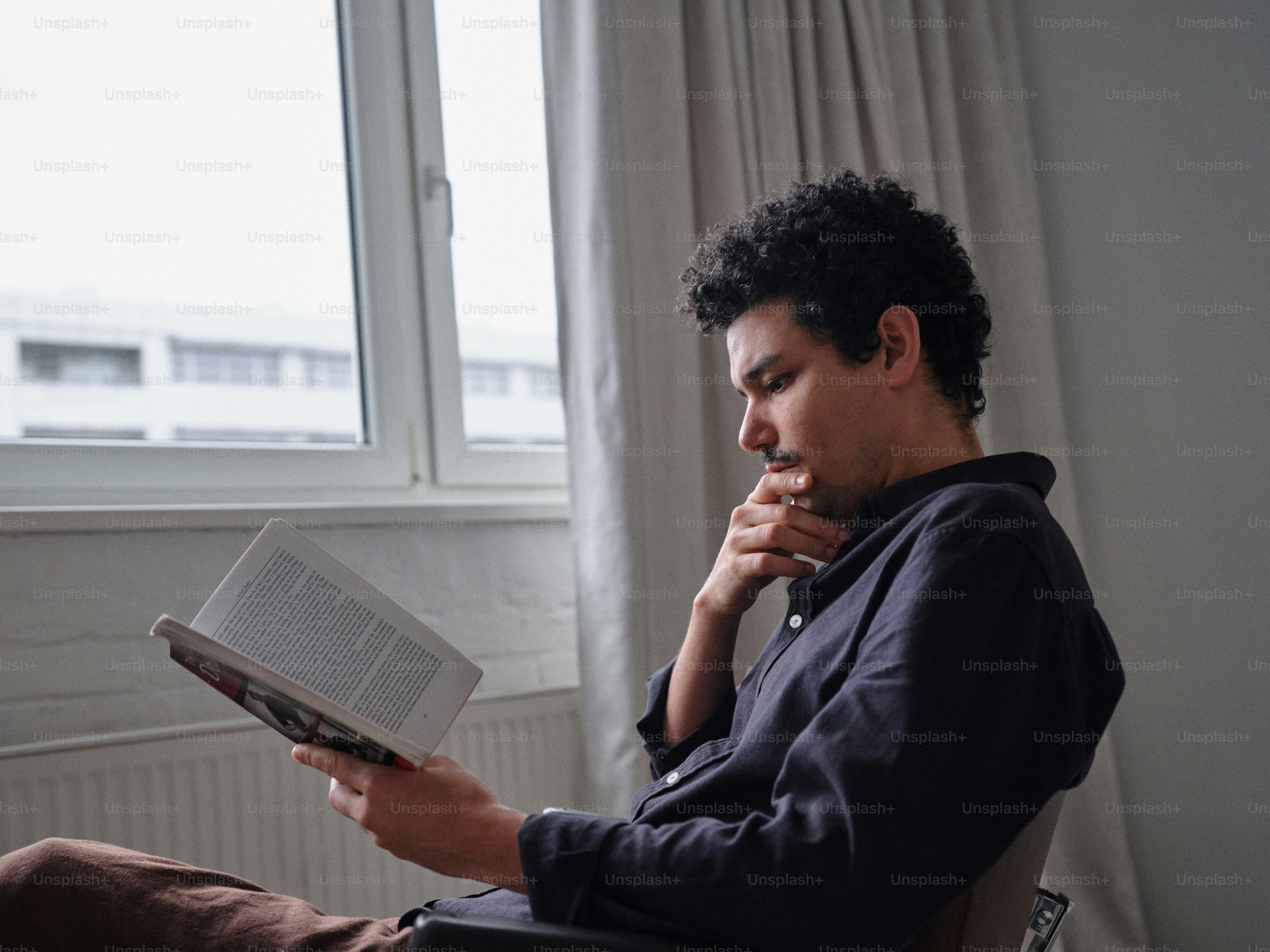 Ein Mann sitzt auf einem Stuhl und liest ein Buch