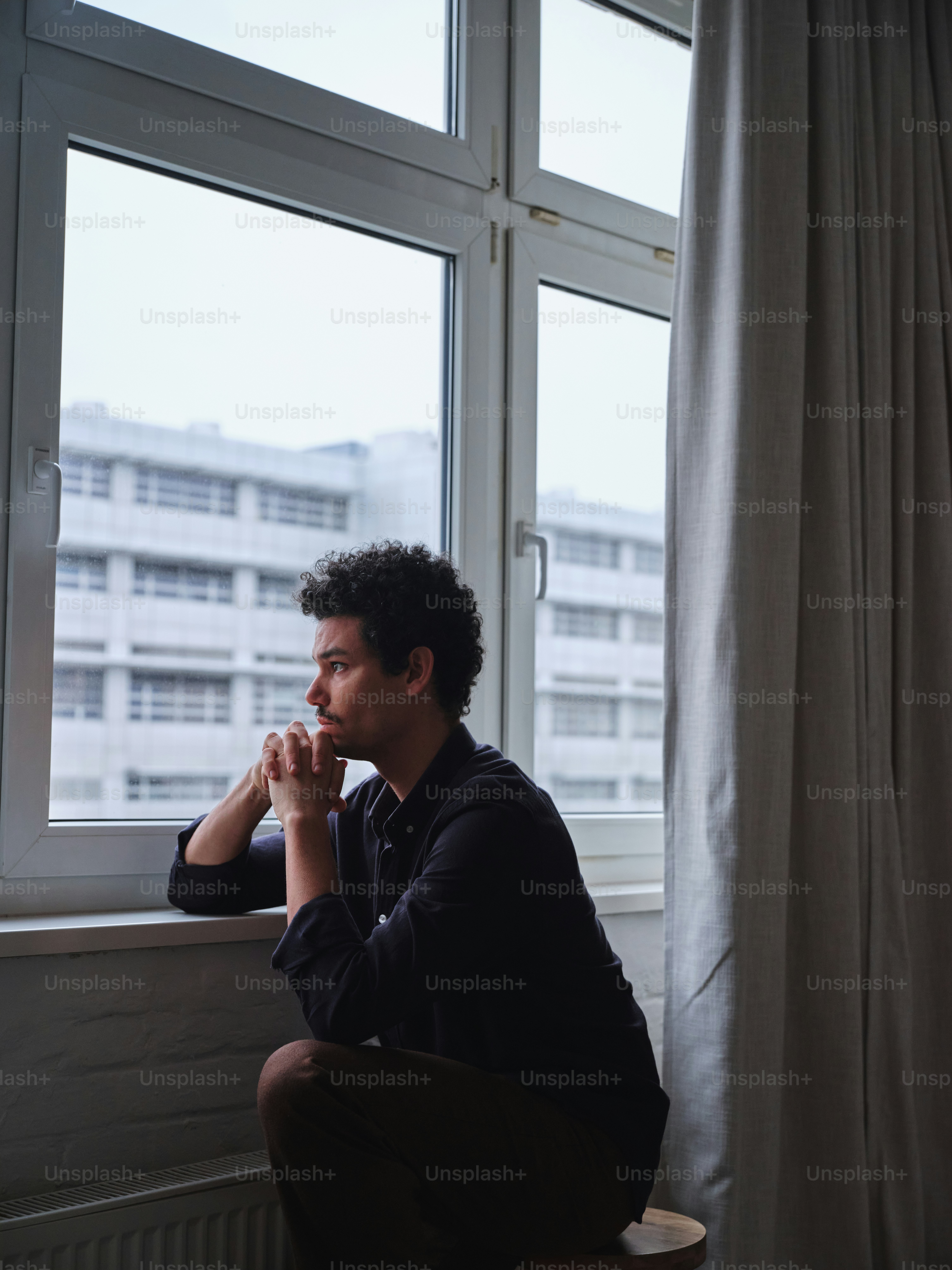 A man sitting in a chair looking out a window