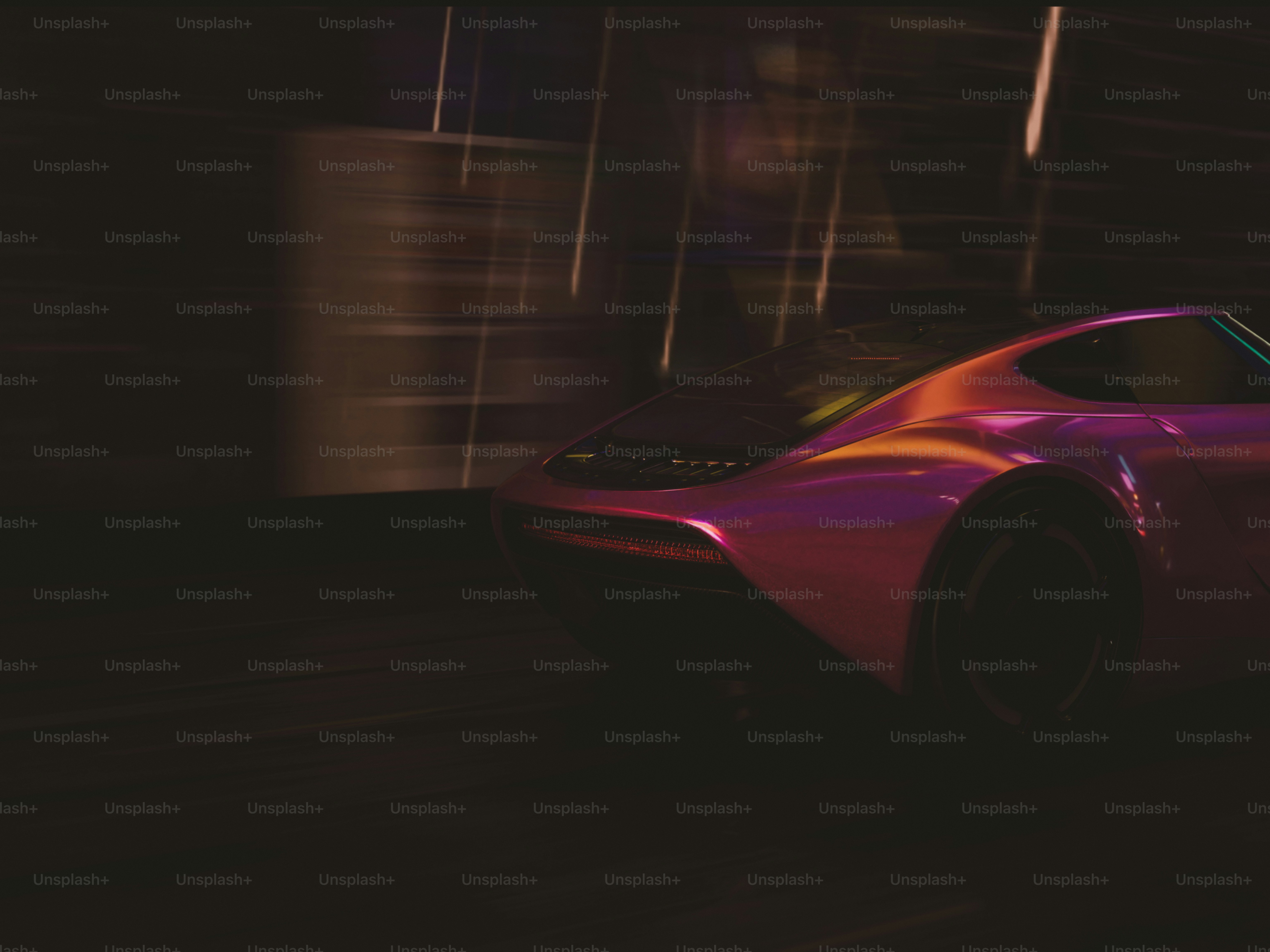 A red sports car driving down a street at night