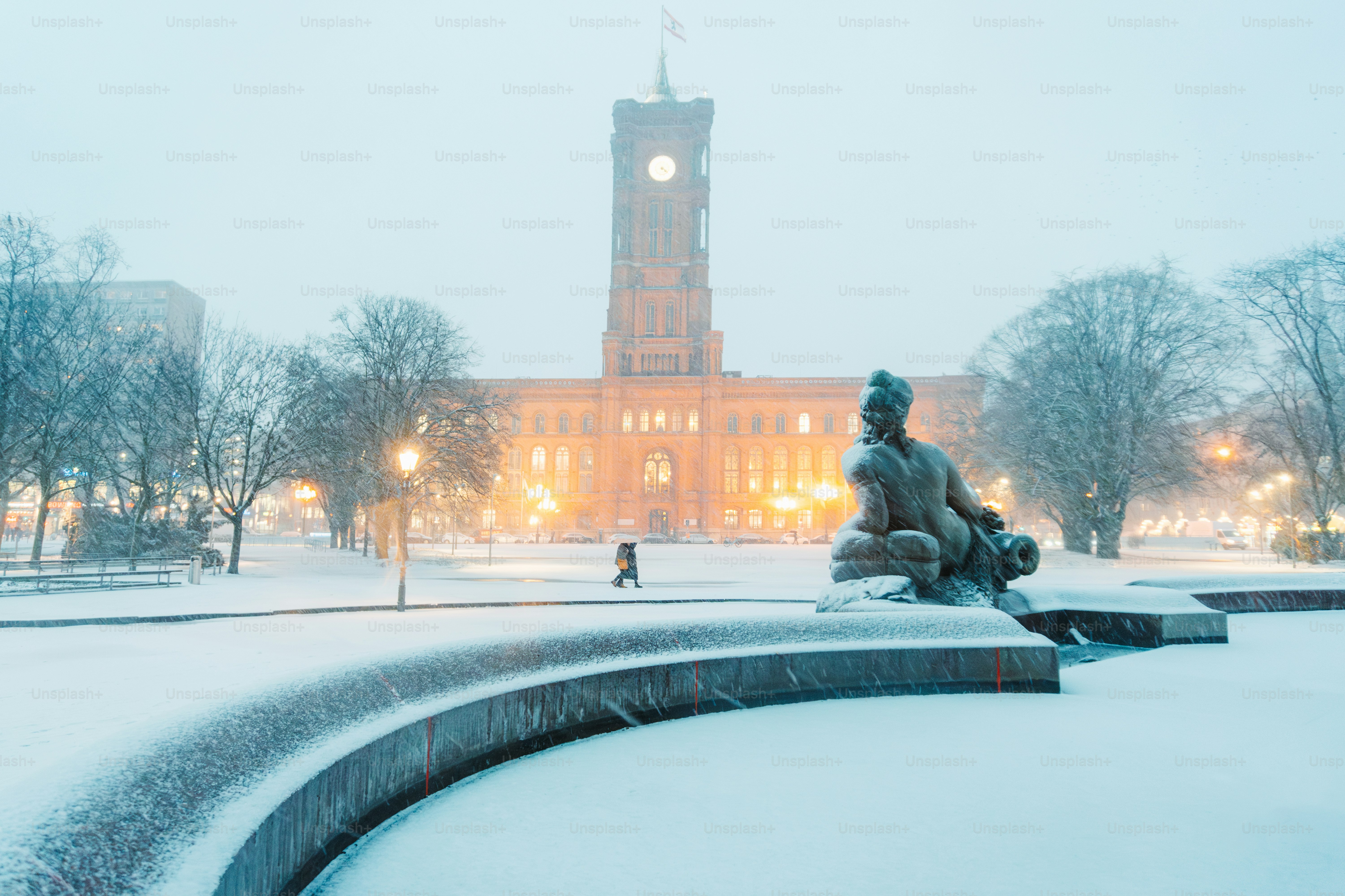 A statue of a person sitting on a bench in the snow