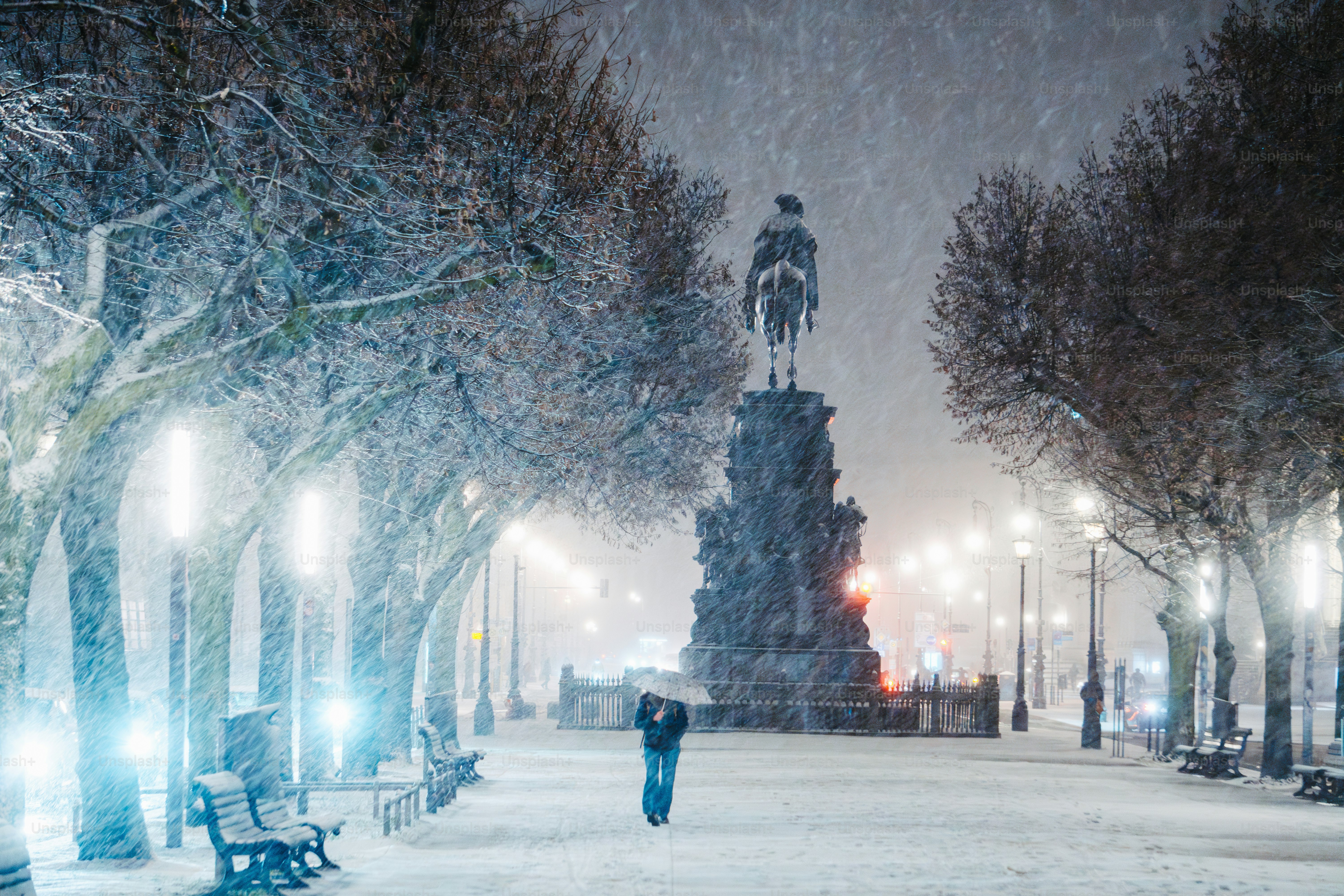 A person walking in a snowy park at night