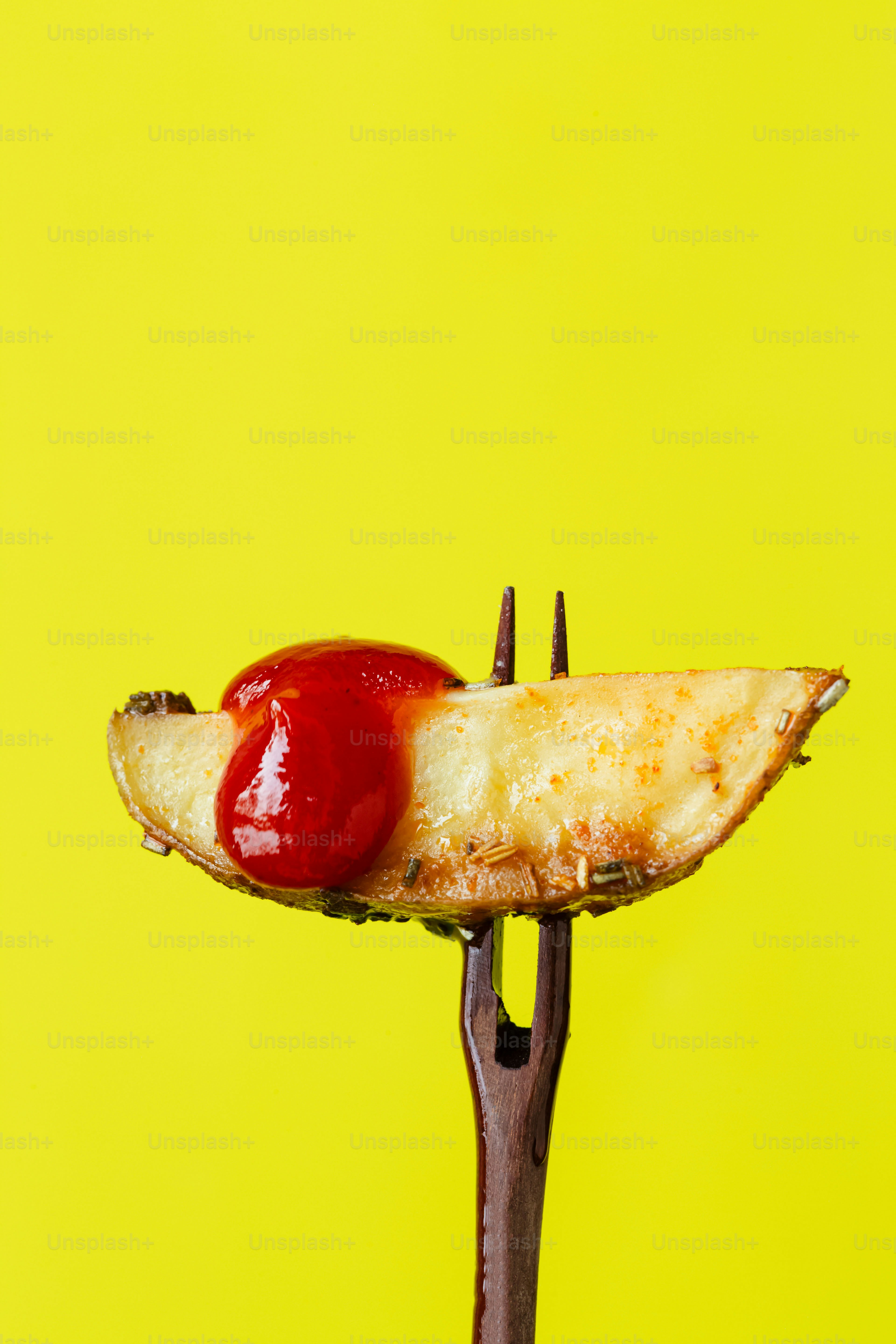 Una banana e ketchup su una forchetta su sfondo giallo