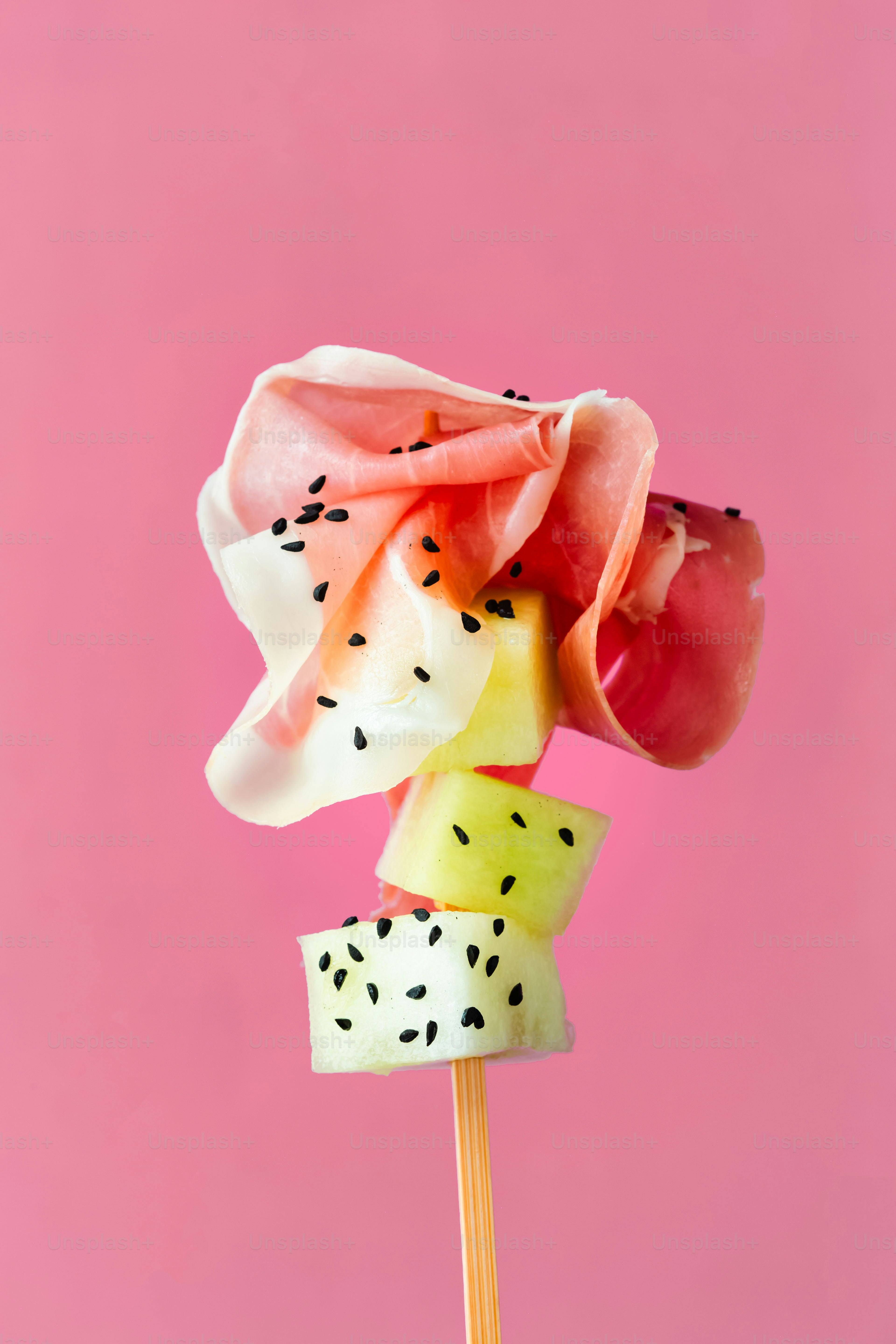 Un lecca-lecca con frutta su un bastoncino su sfondo rosa
