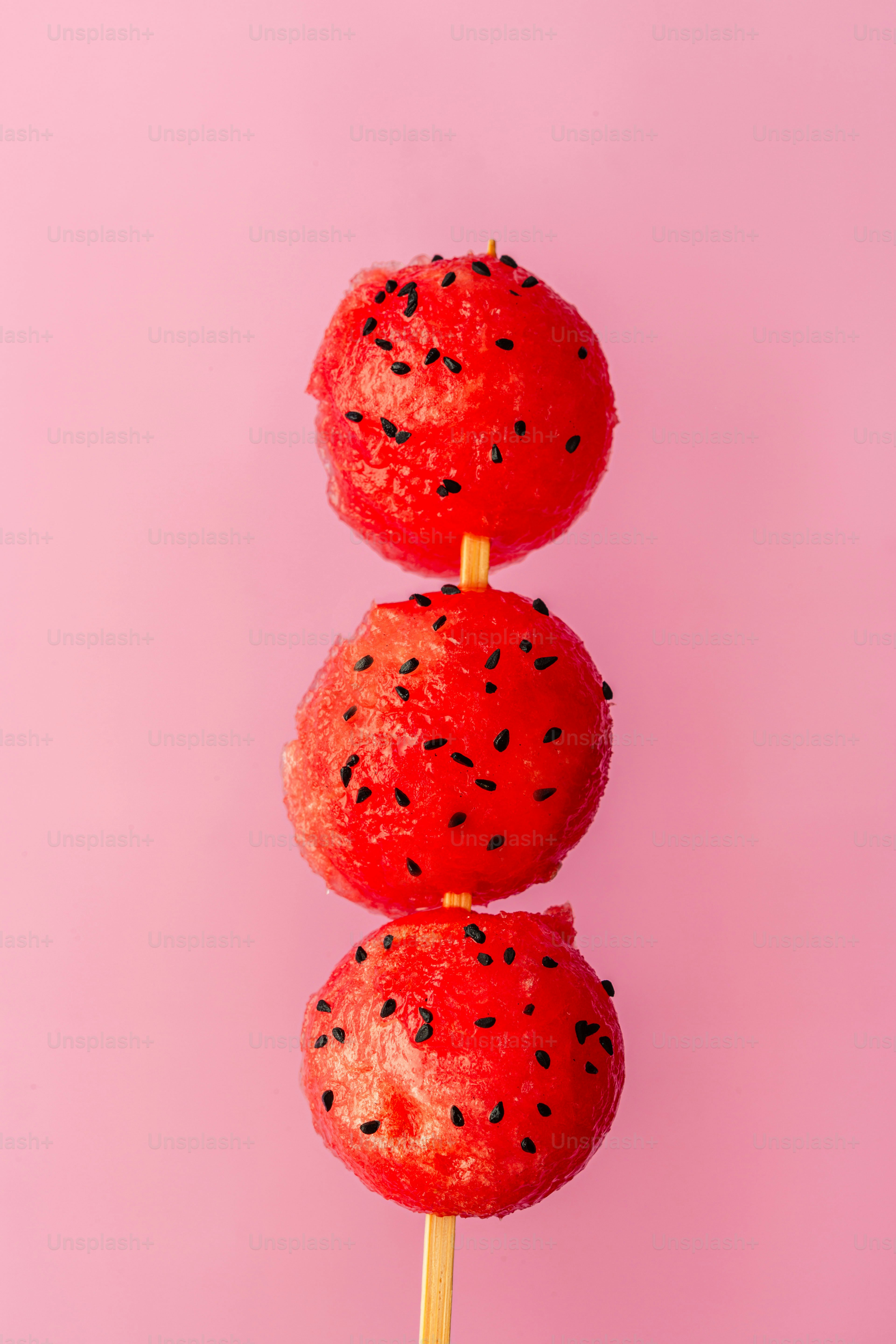 Three watermelon lollipops on a stick on a pink background
