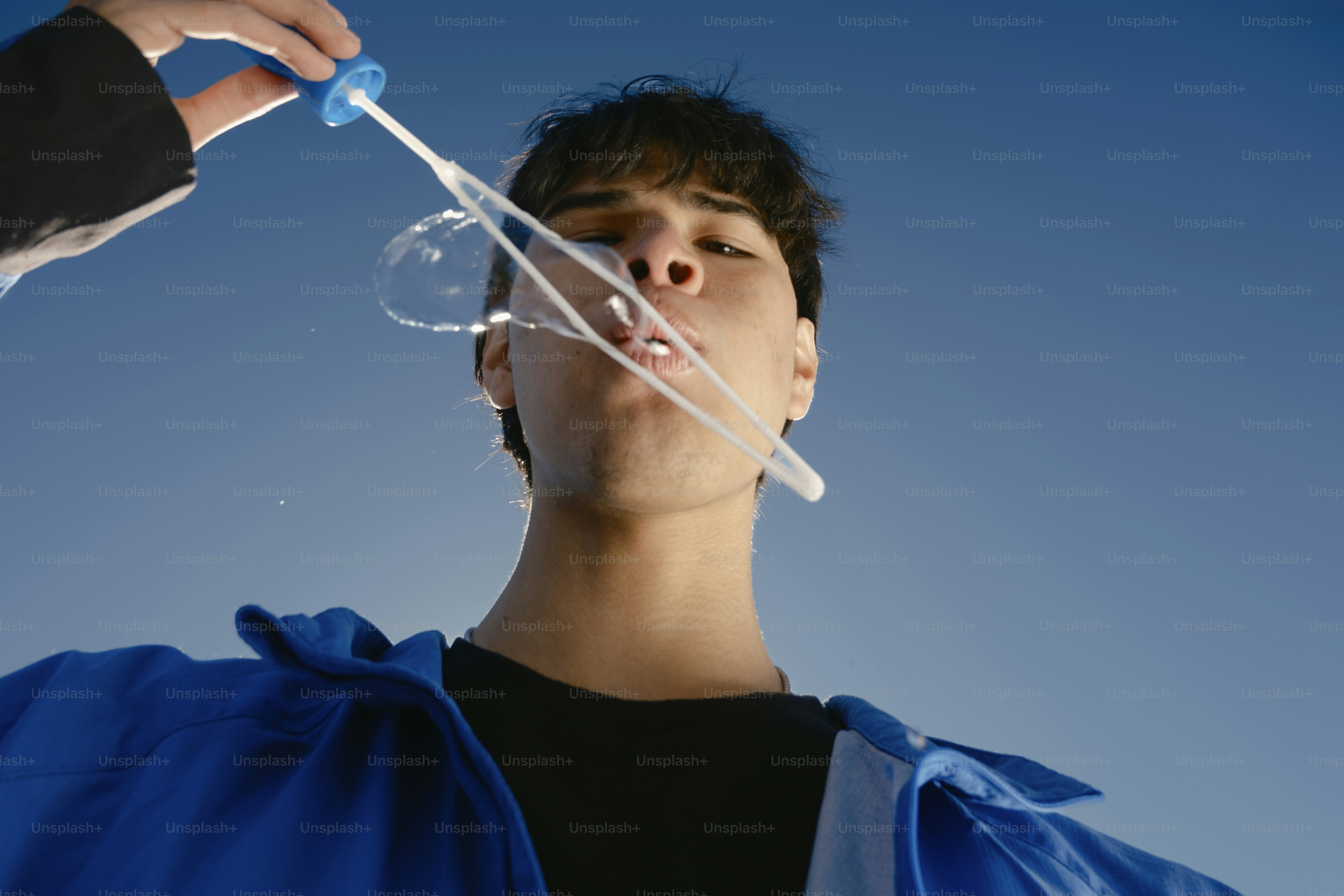 A man blowing a bubble with a plastic wand