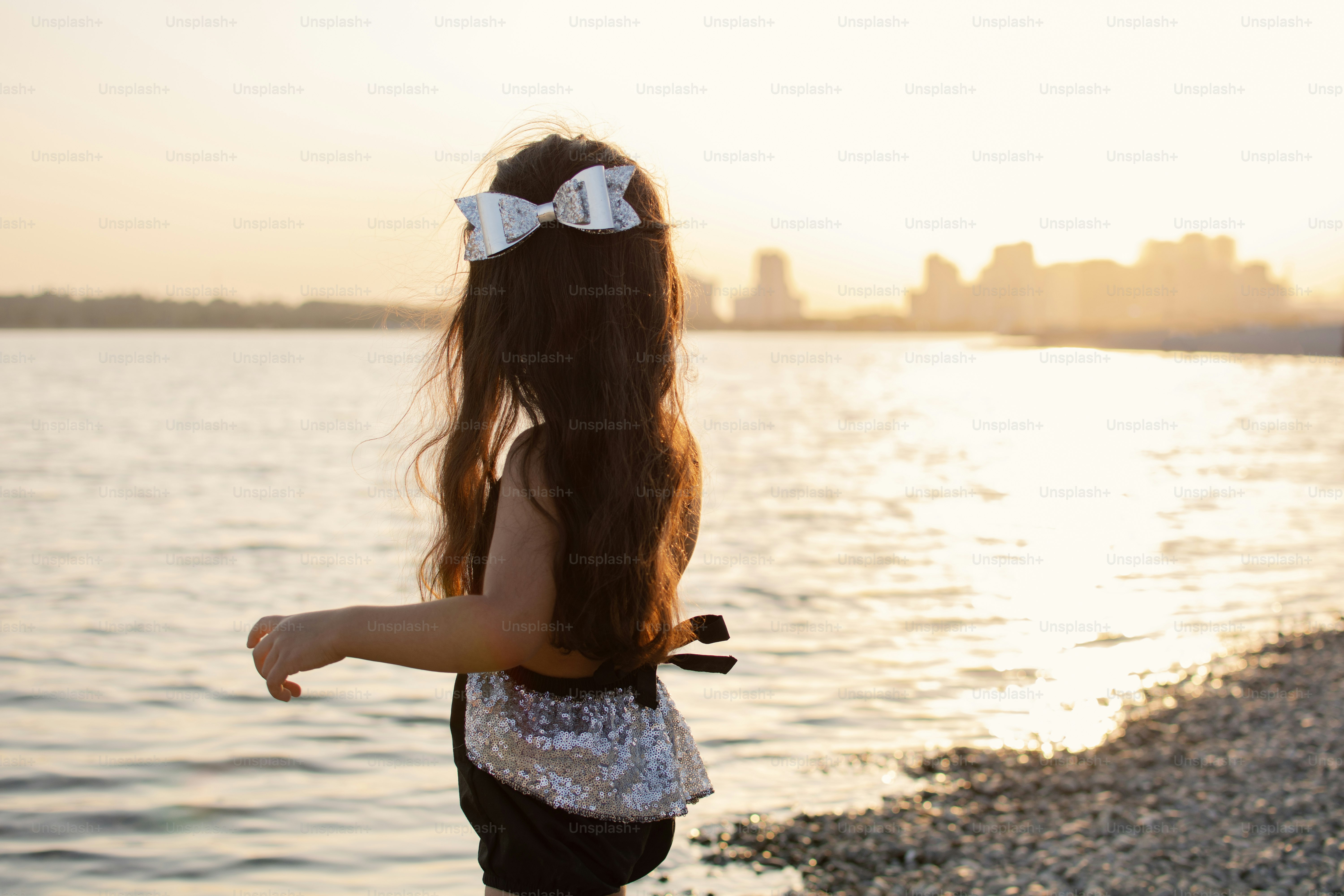 A woman standing on a beach next to a body of water photo – Outdoors ...