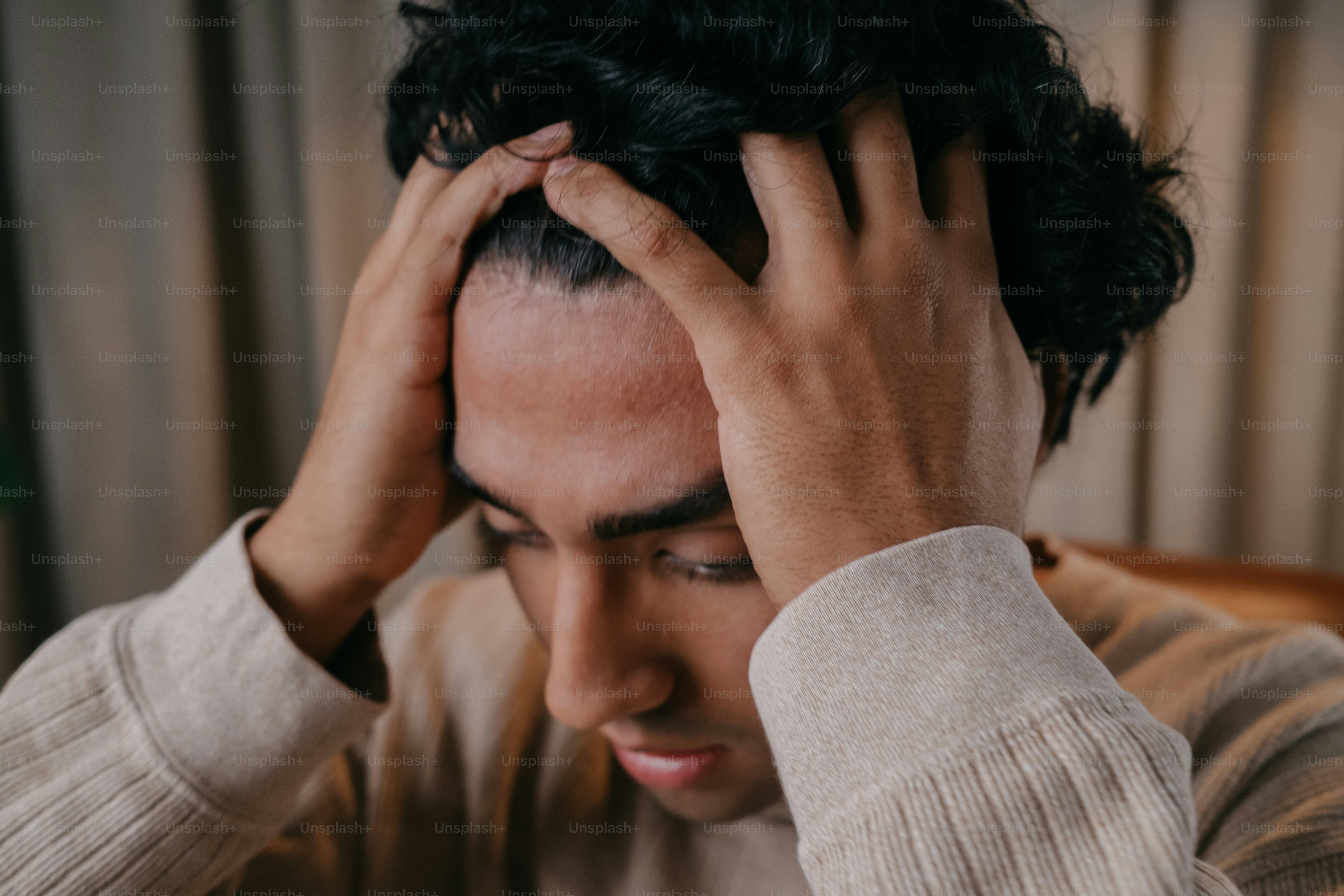 A man sitting in a chair with his hands on his head