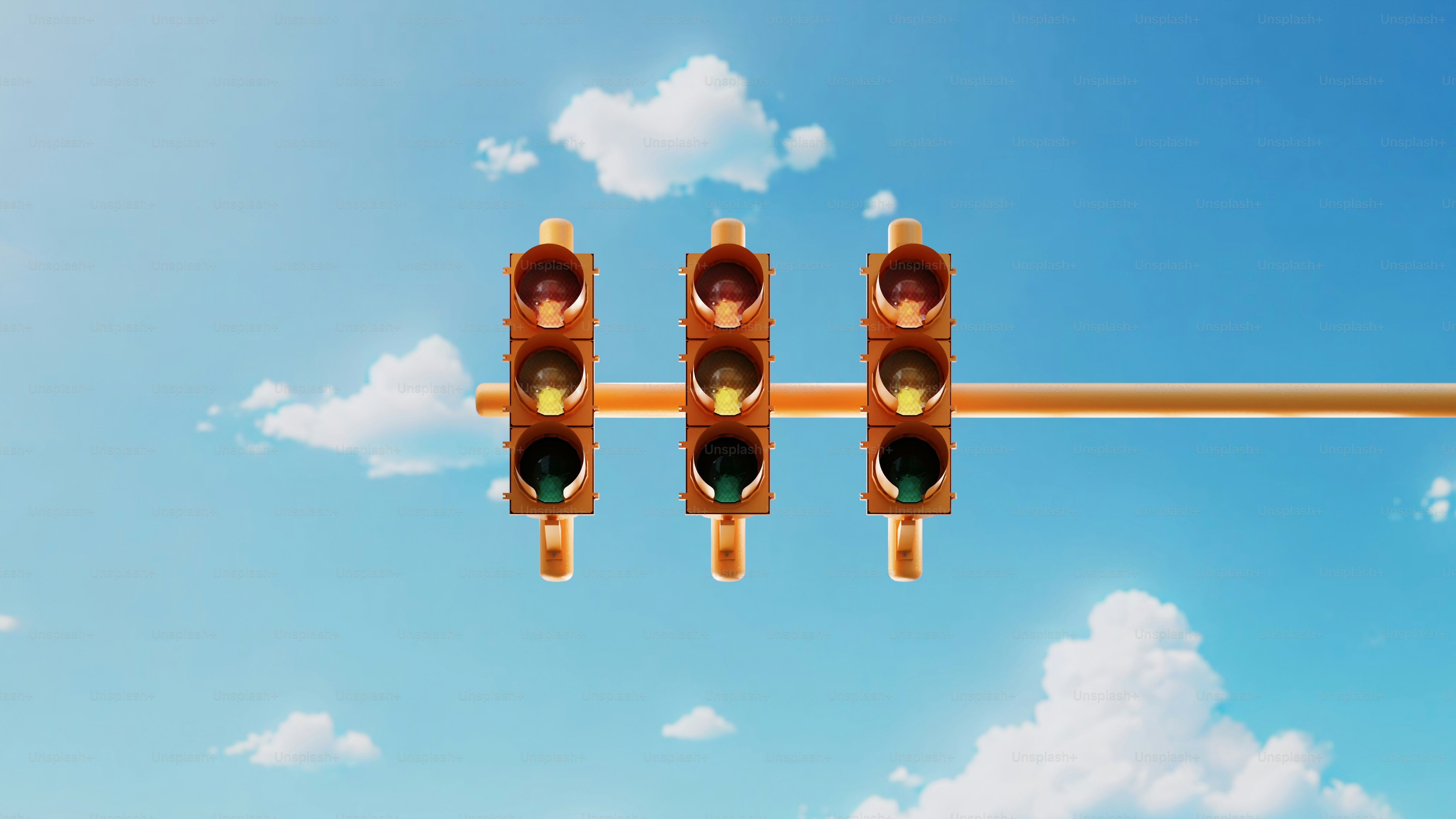 Three traffic lights on a yellow pole with a blue sky in the background