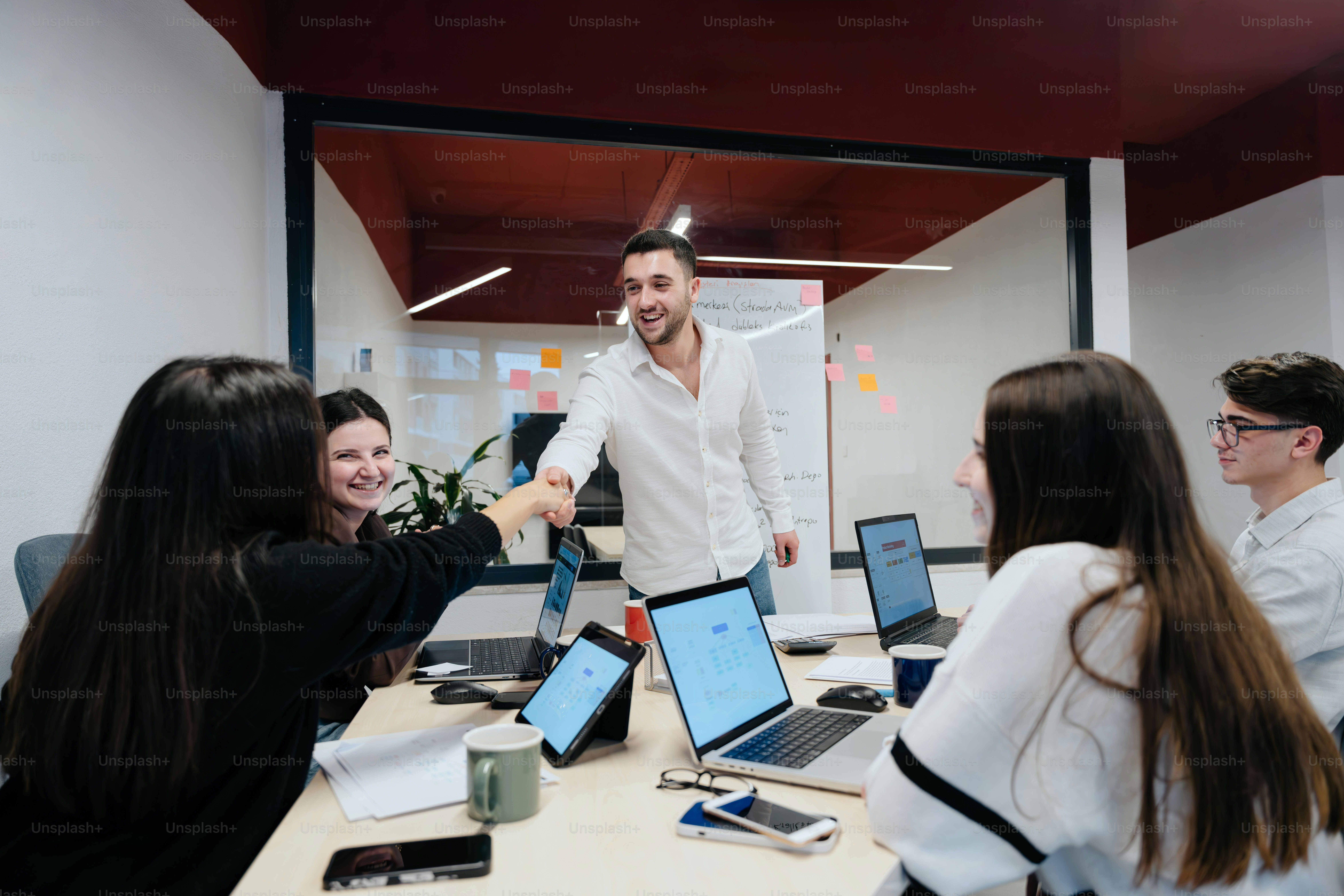 A group of people sitting around a table with laptops photo – Office ...