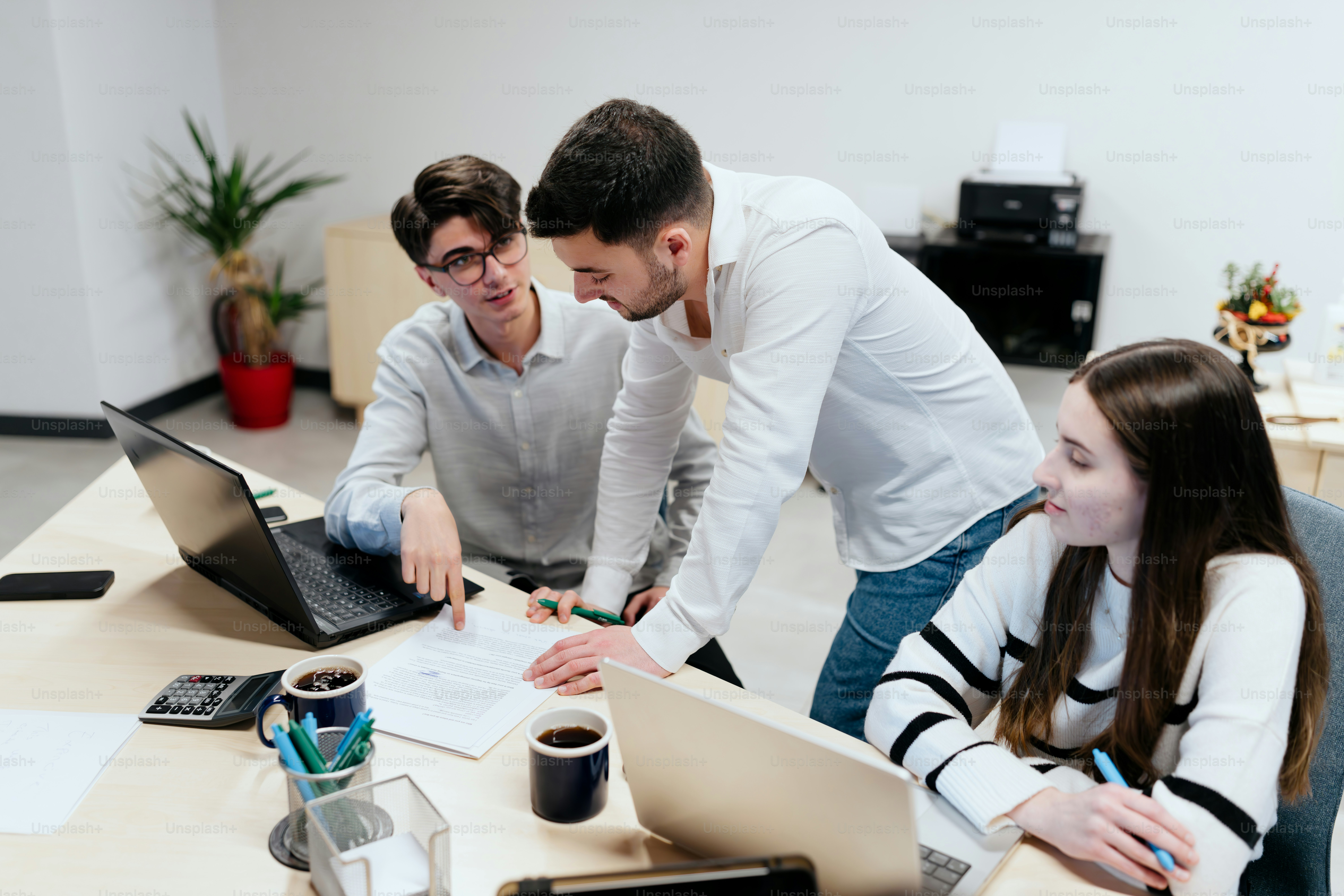 A group of people sitting around a table with laptops photo – Office ...