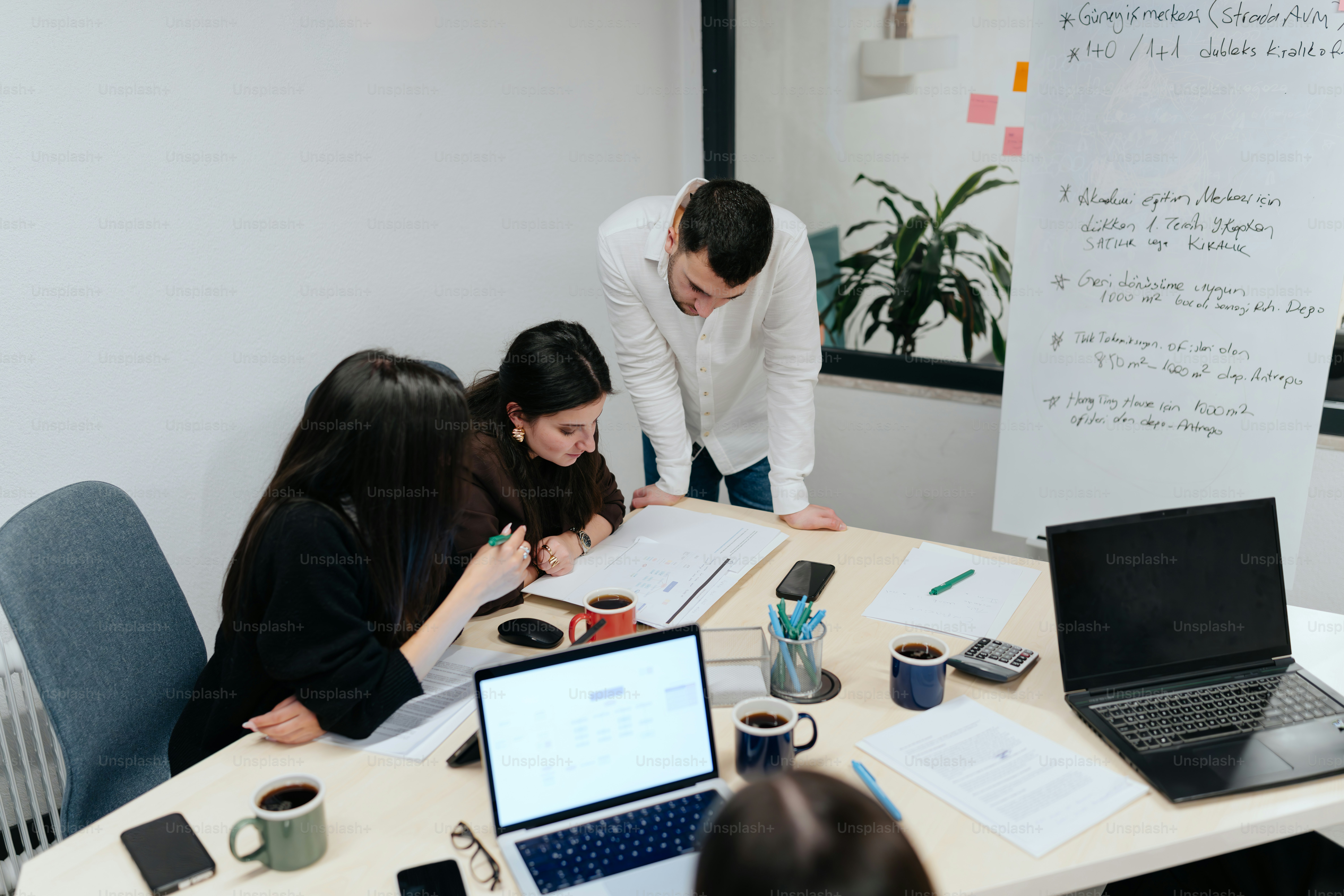 A group of people sitting around a table with laptops
