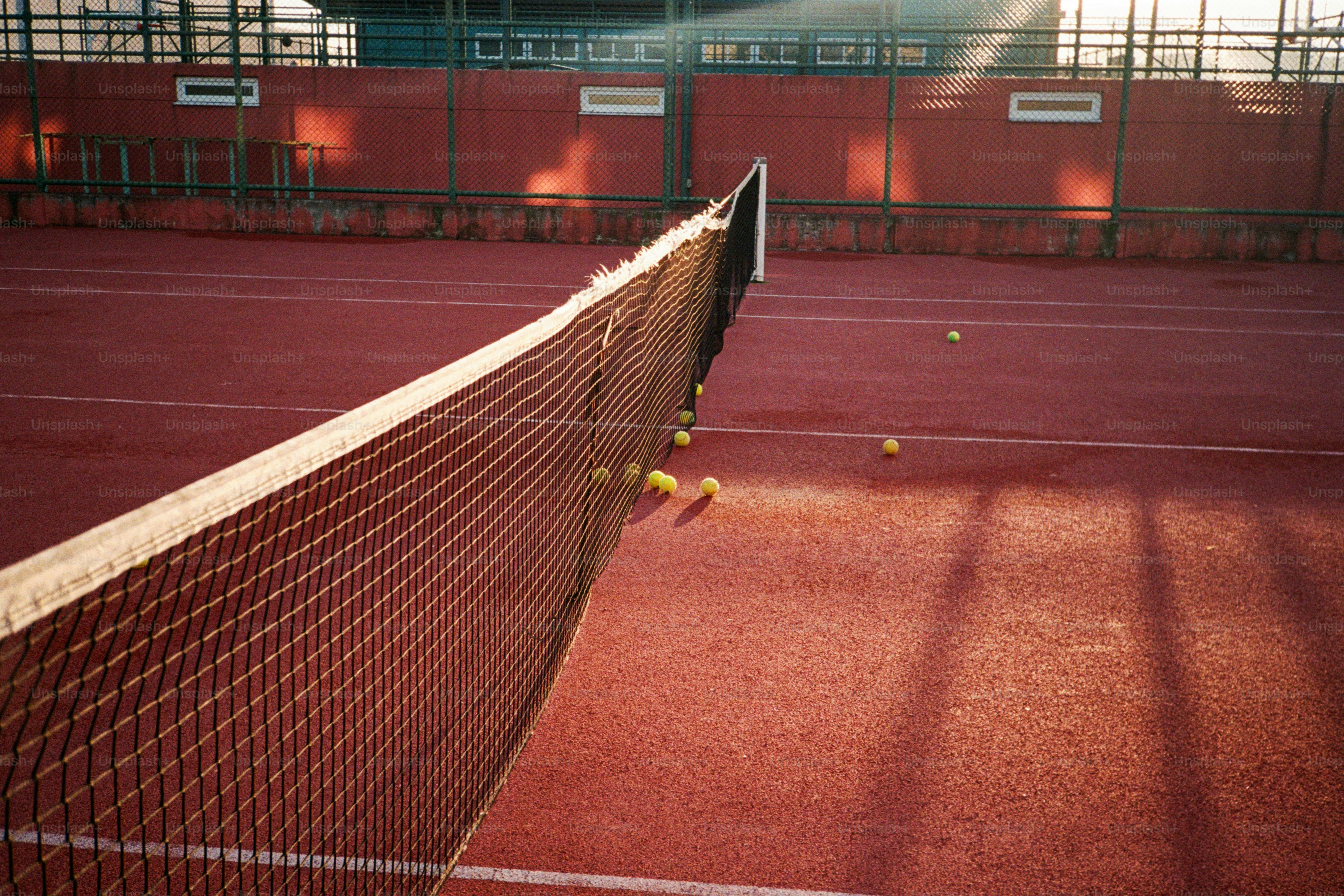 A tennis court with a net and tennis balls