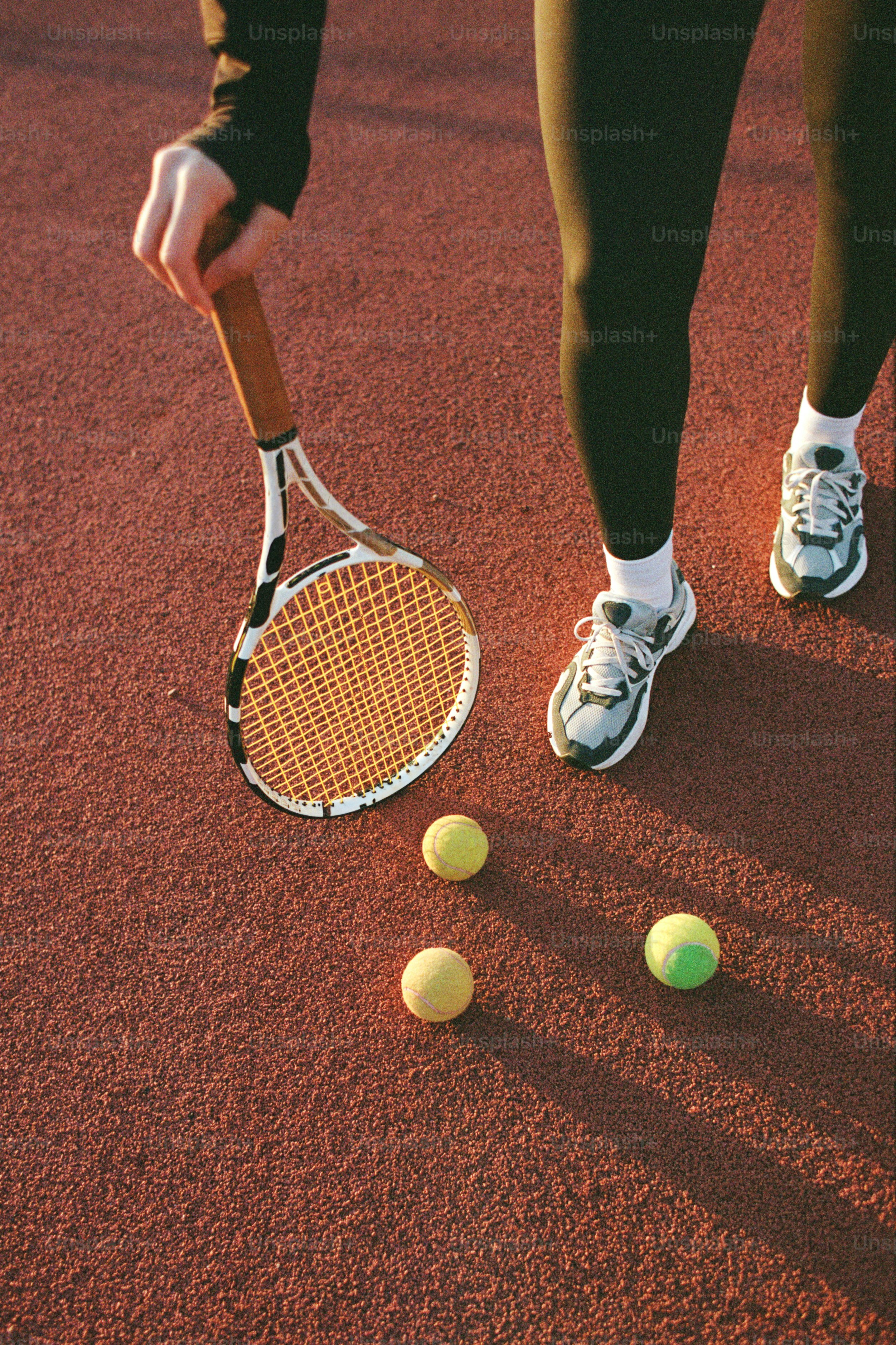 A person with a tennis racket and two tennis balls