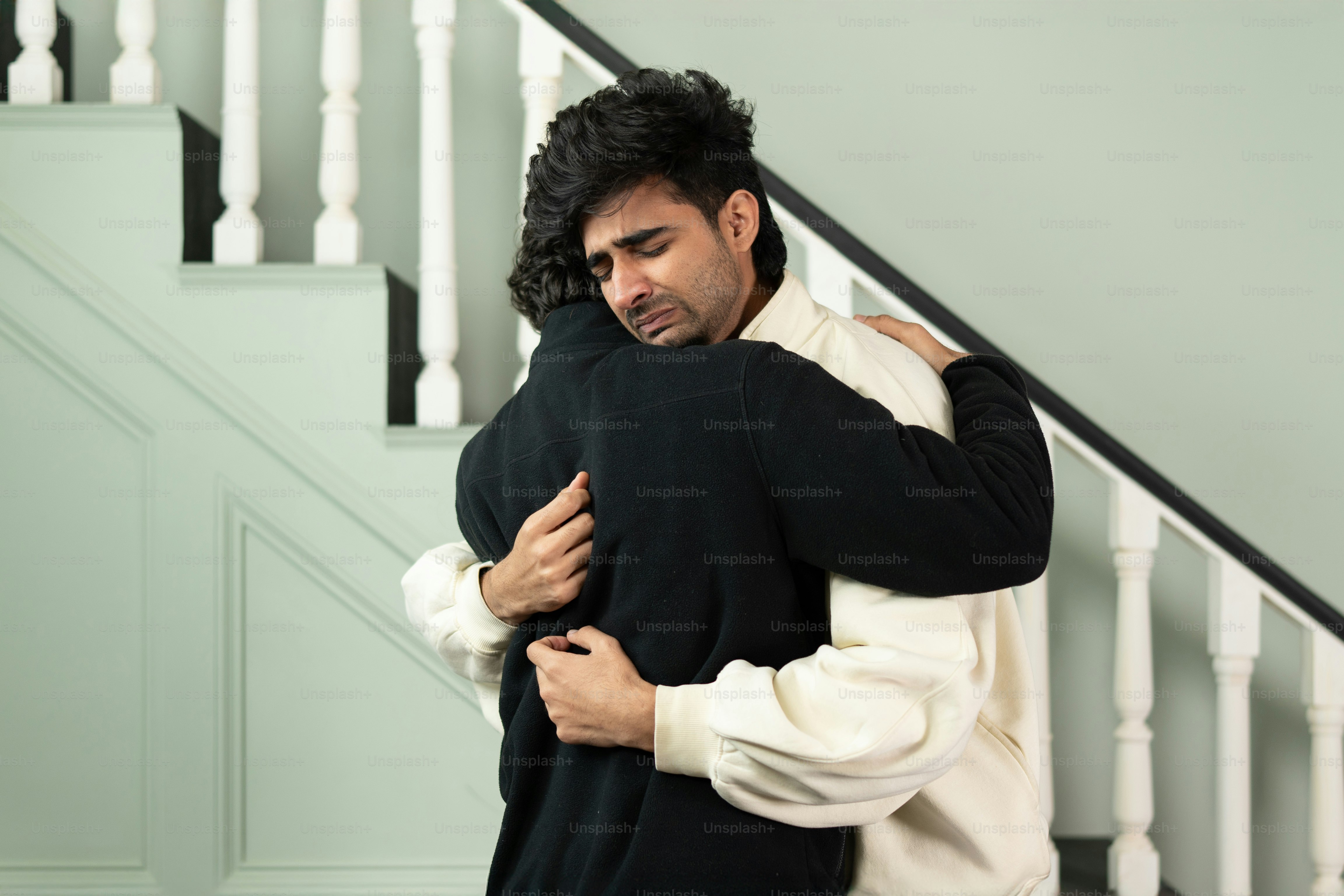A man hugging another man in front of a staircase photo – Support Image ...