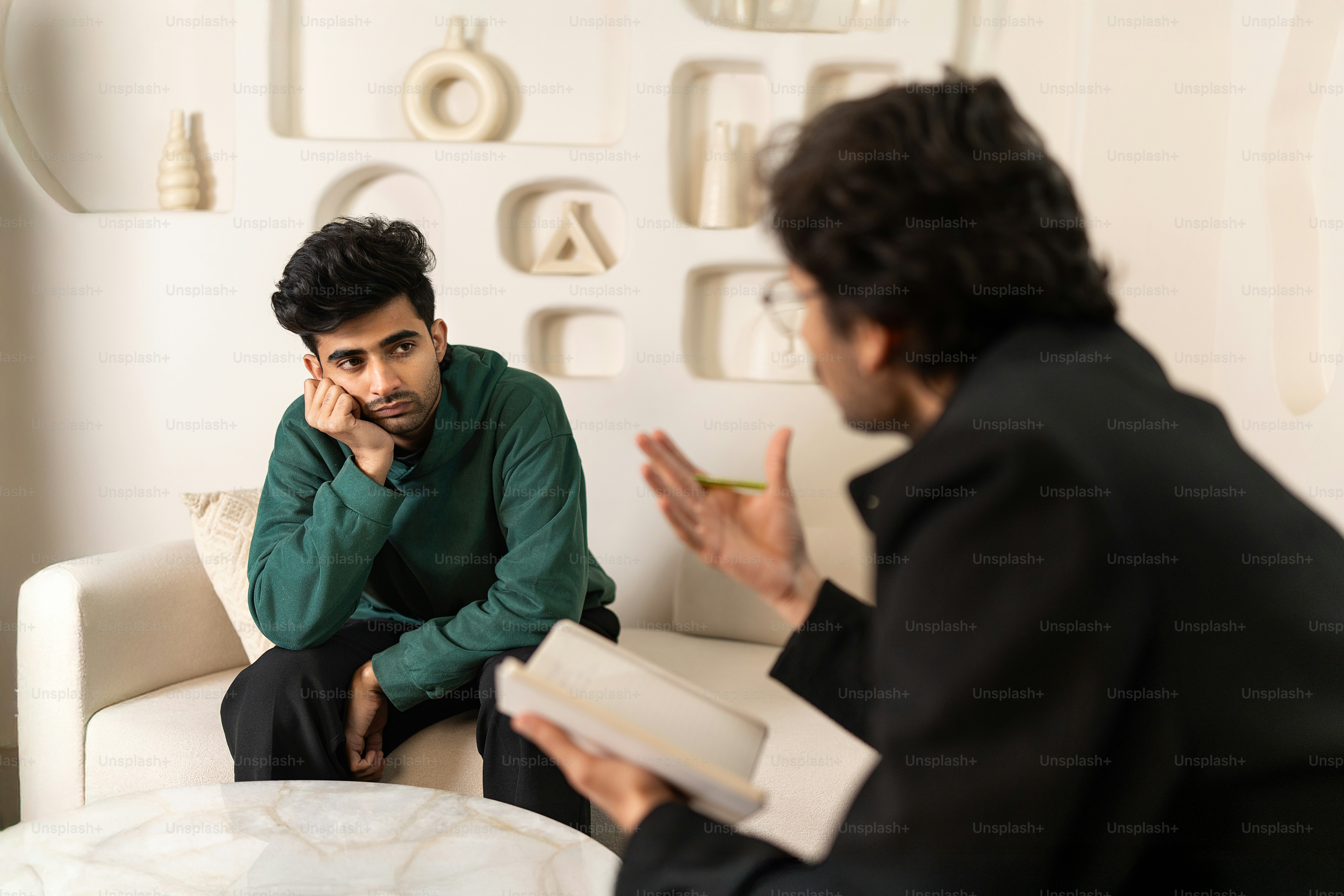 Two men sitting on a couch talking to each other