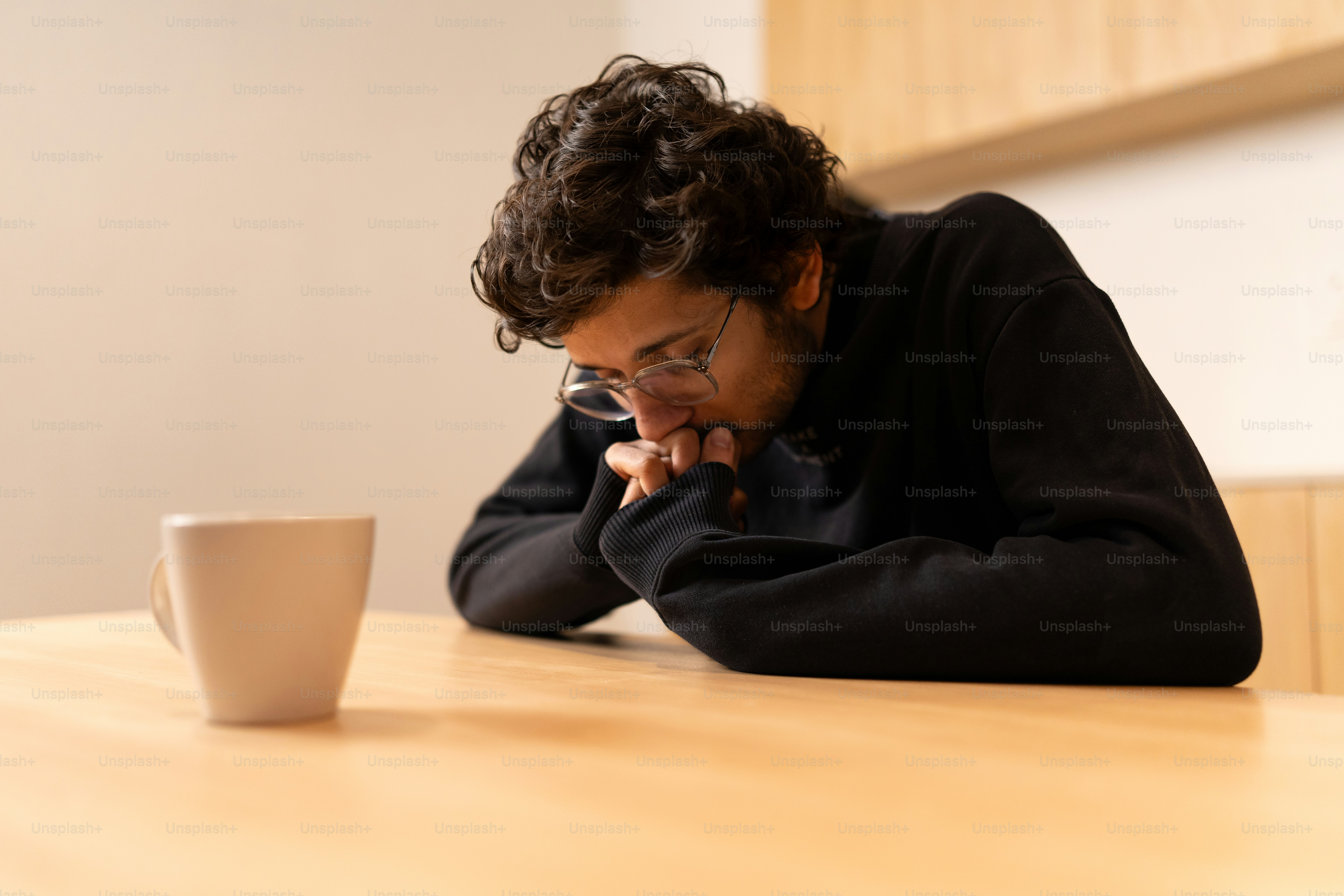 A man sitting at a table with a coffee cup in front of him