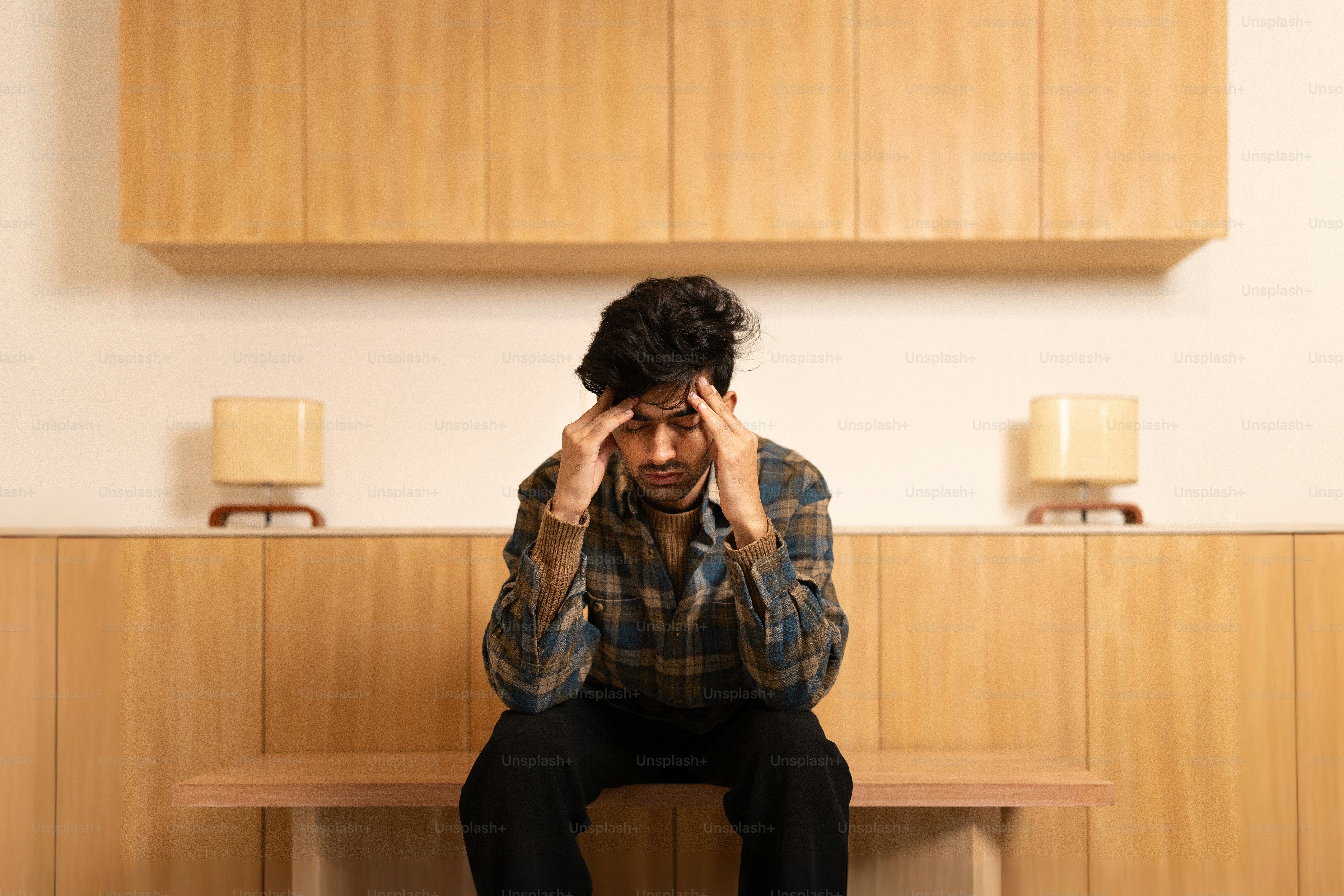 A man sitting on a bench with his head in his hands