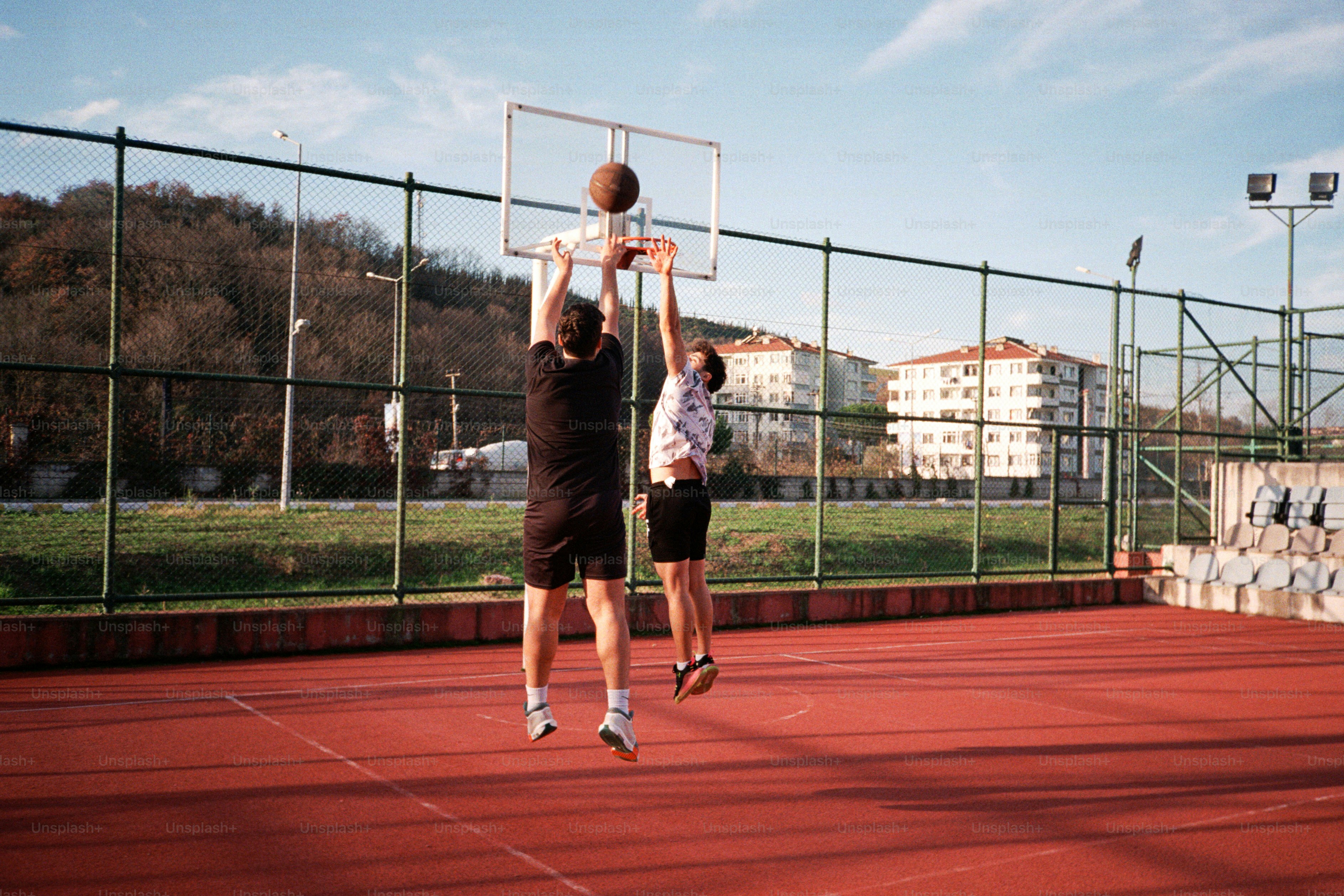 Two men playing basketball on a tennis court