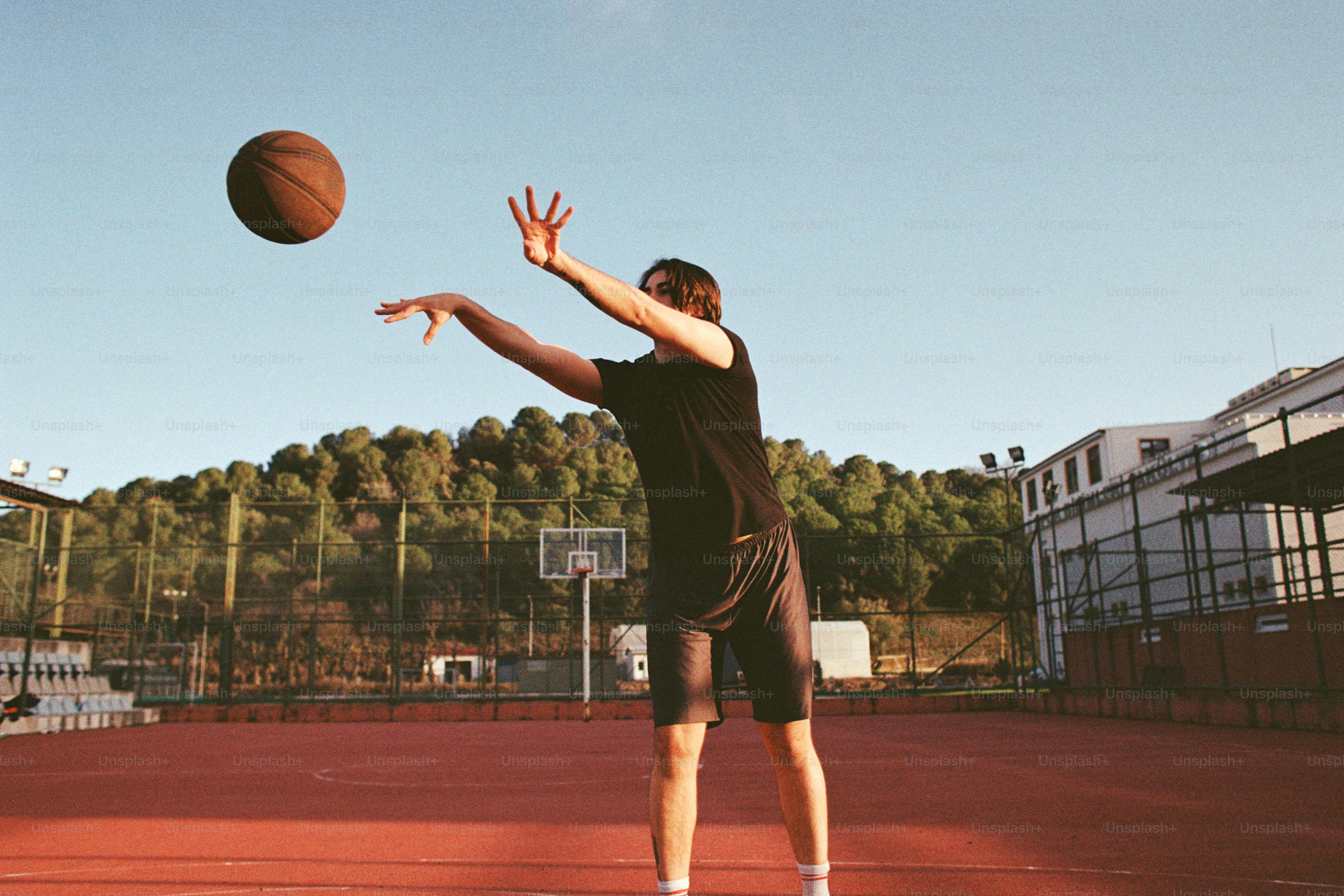 A man standing on a tennis court holding a basketball
