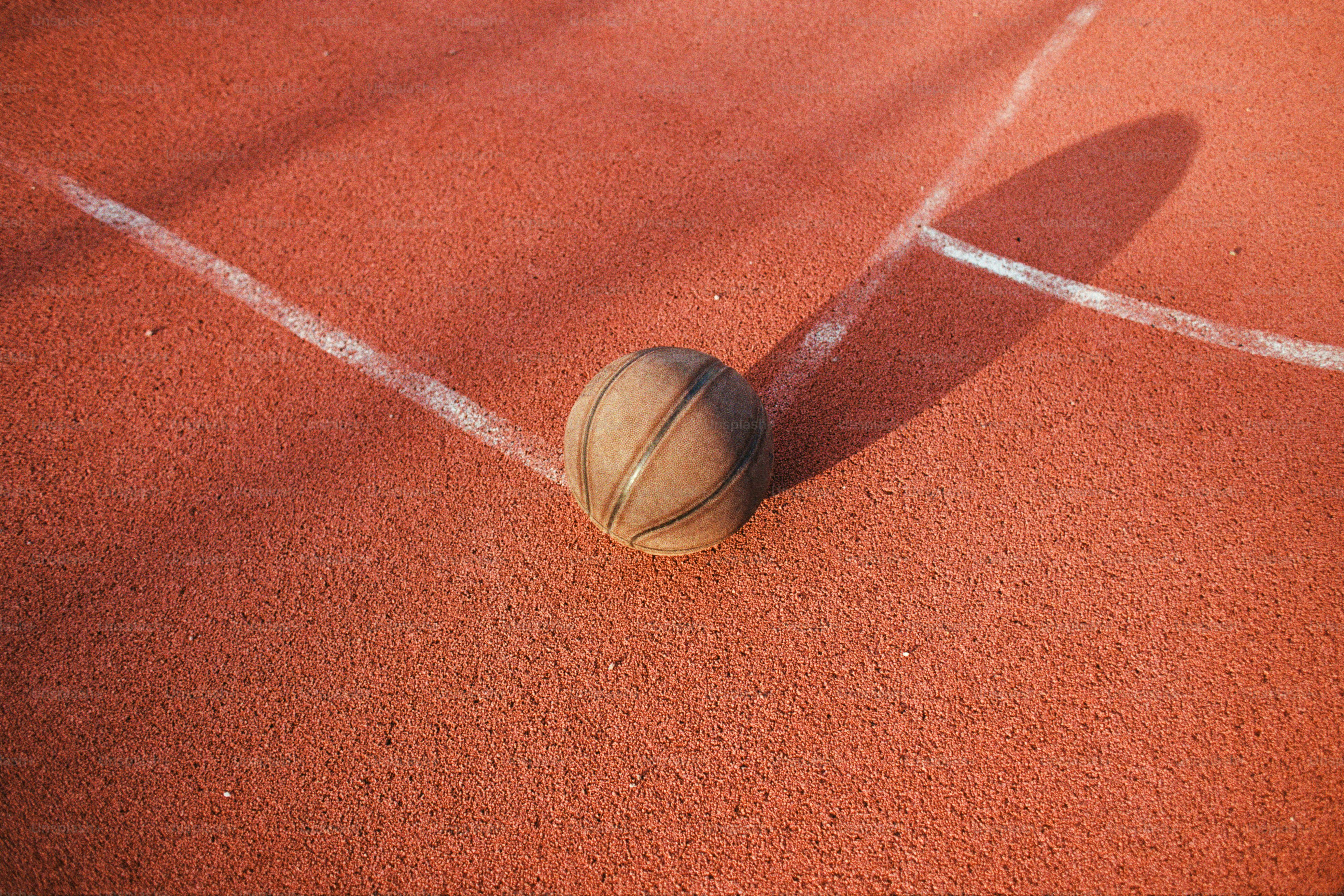 A tennis ball on a court with a line in the background