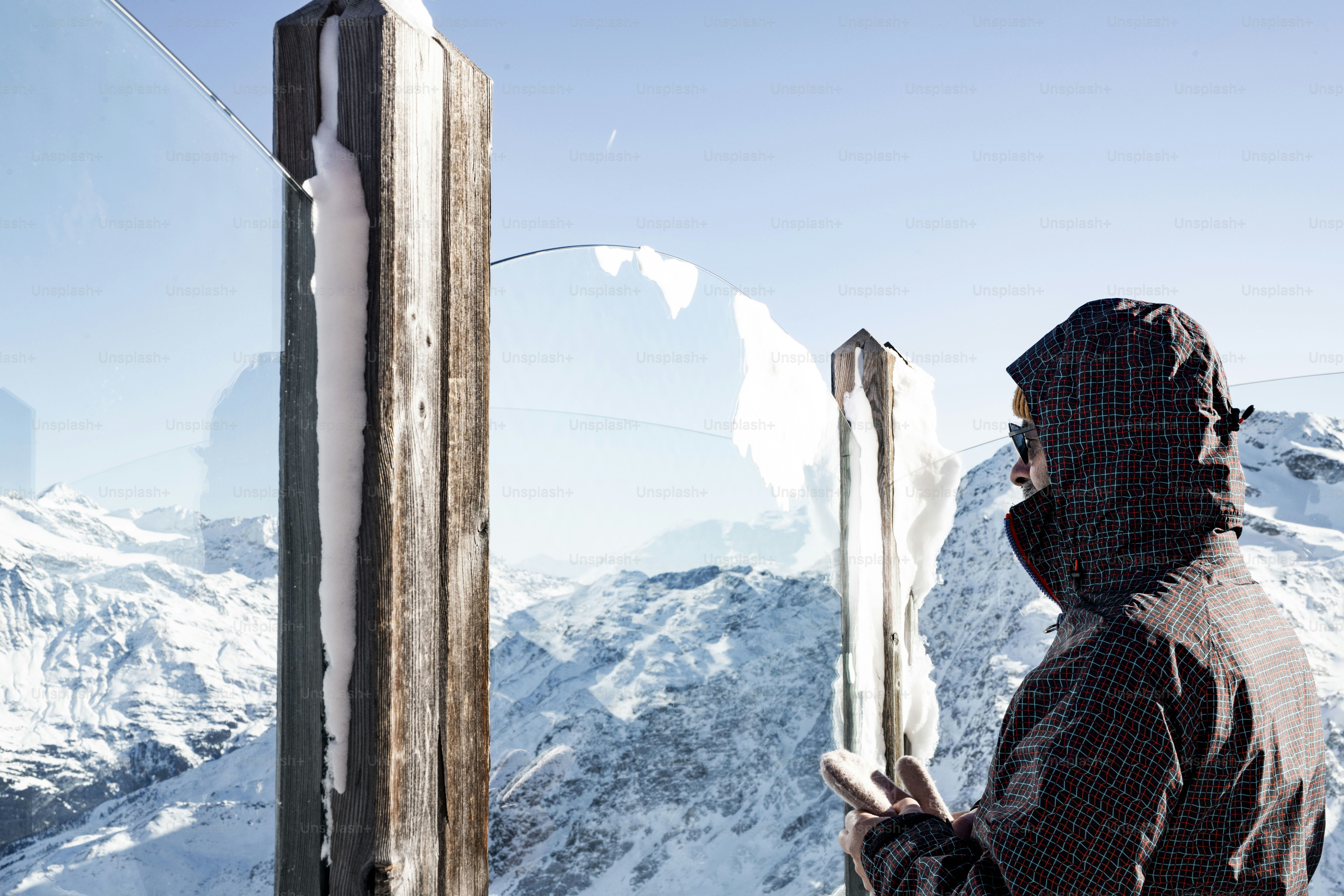 A man holding a pair of skis on top of a snow covered mountain