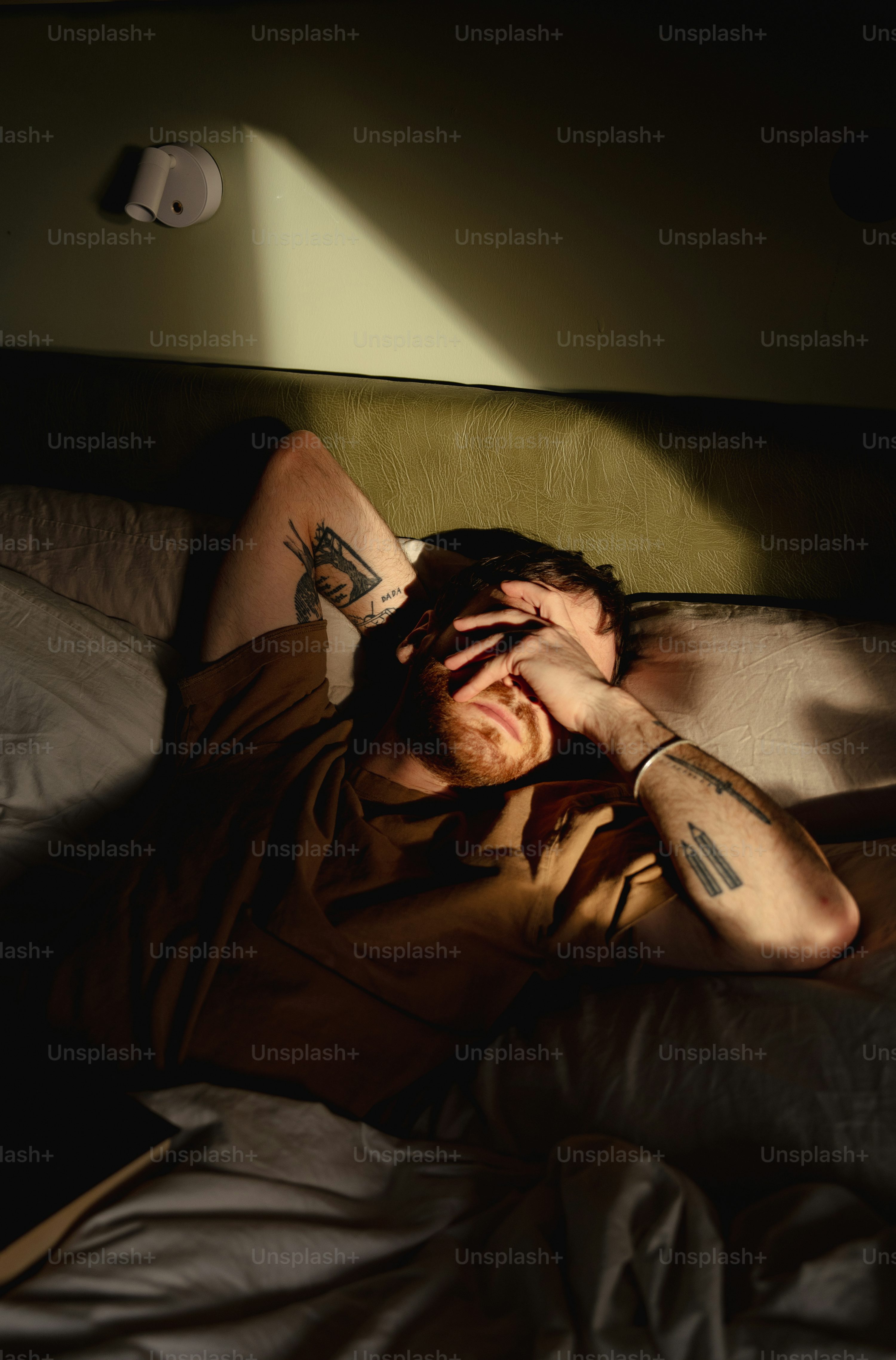 A man laying in bed with his hands on his head