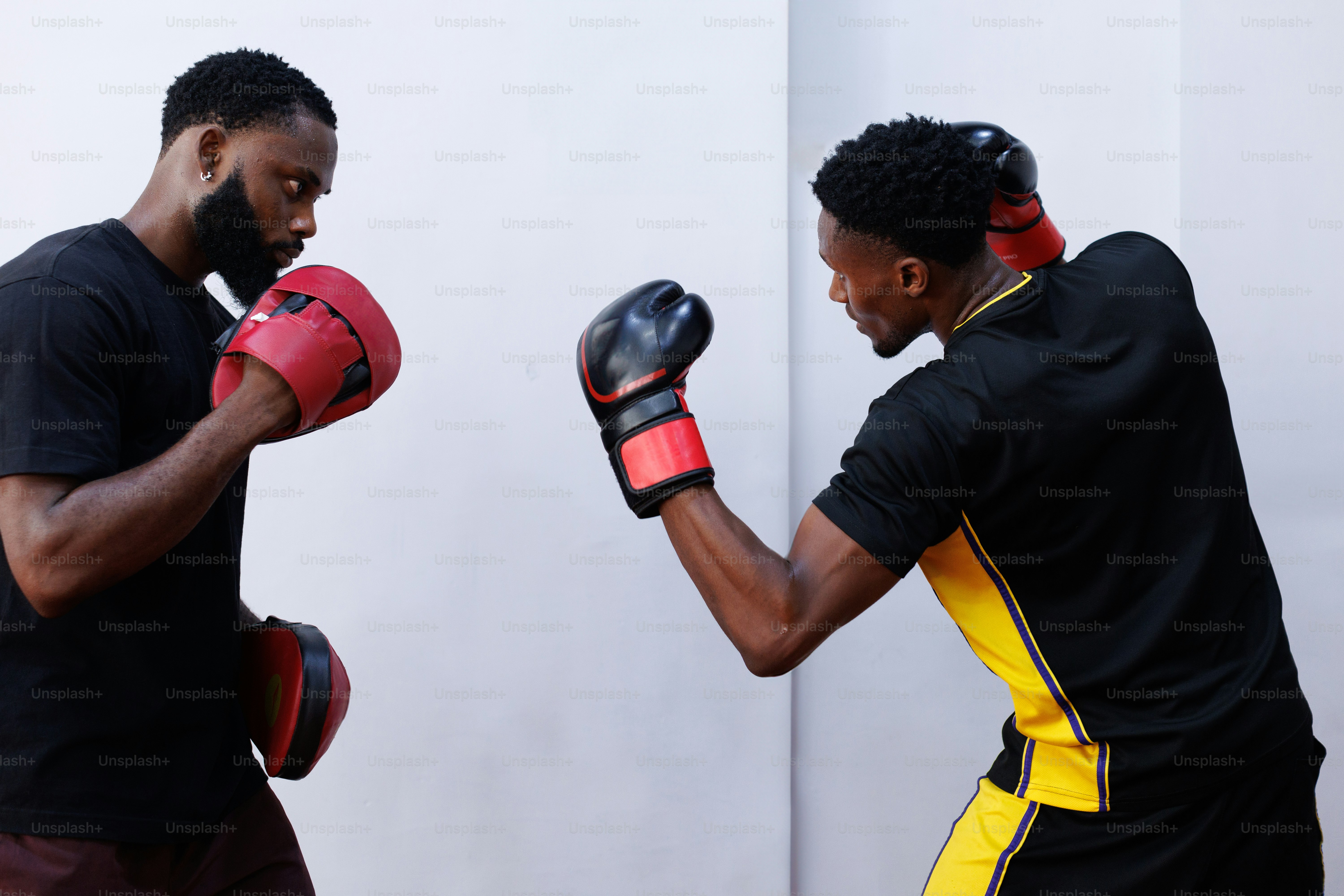 A couple of men standing next to each other wearing boxing gloves