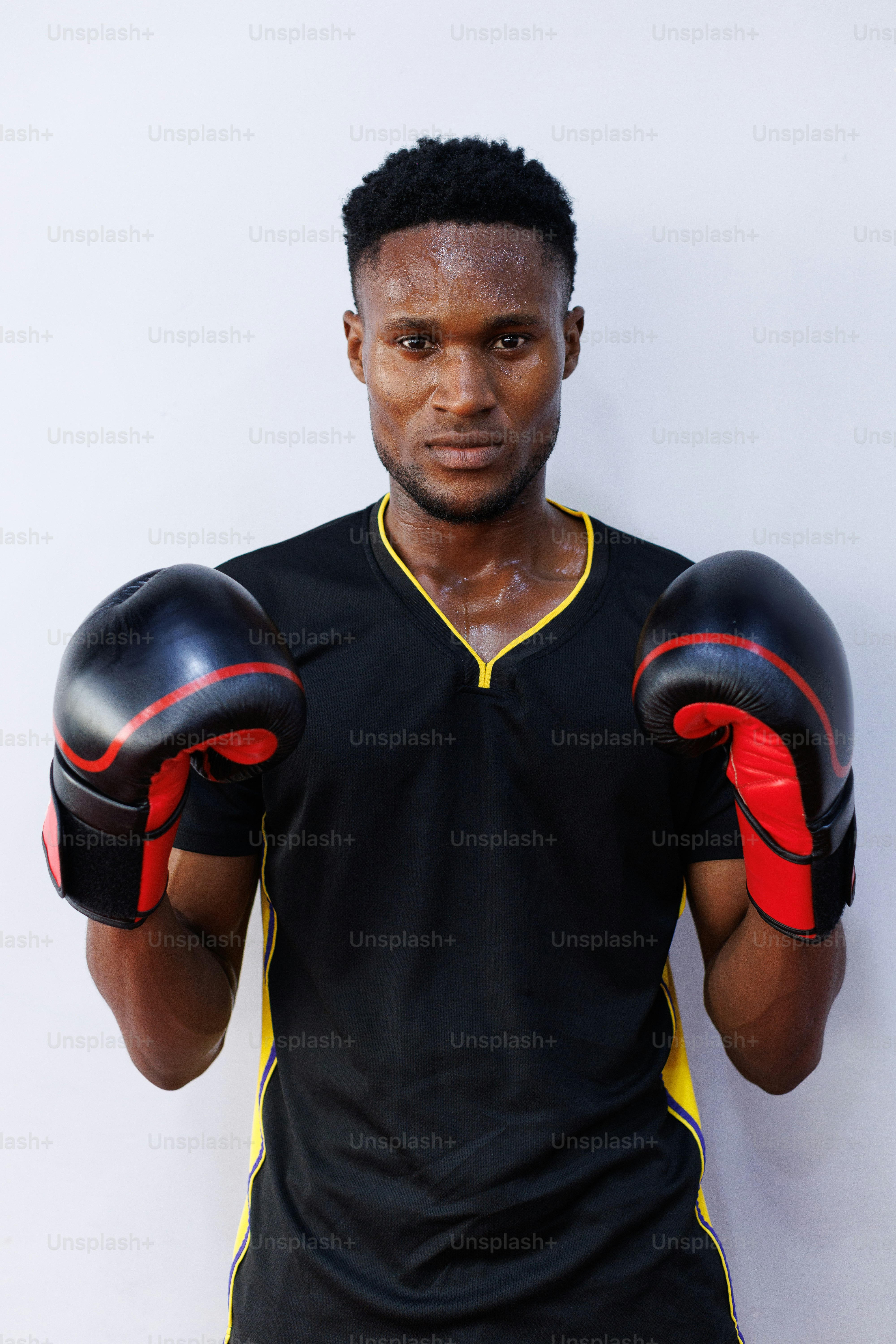 A man in a black shirt and red and yellow boxing gloves