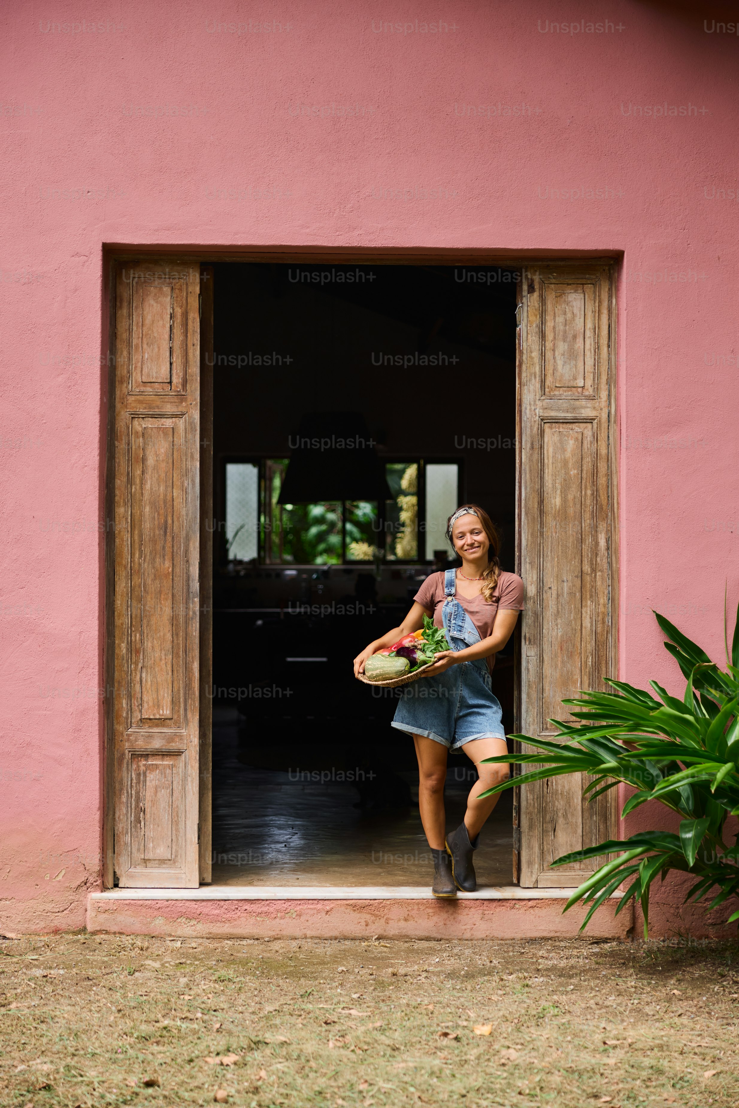 A woman holding a frisbee in front of a pink building