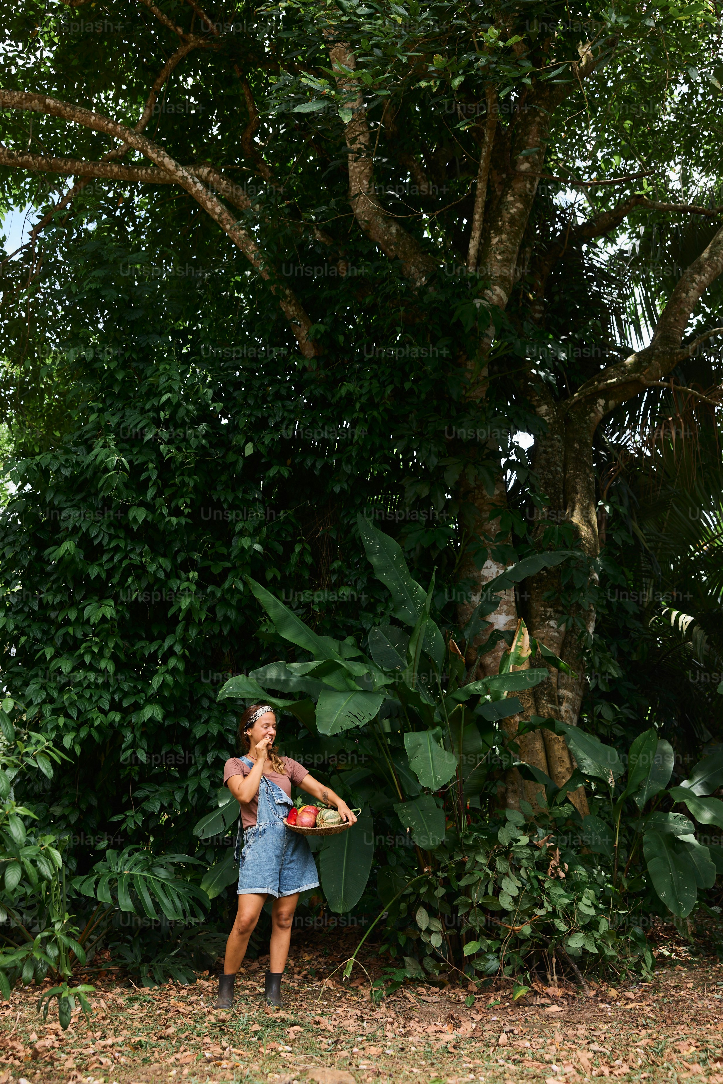 A woman standing in front of a tree holding a frisbee