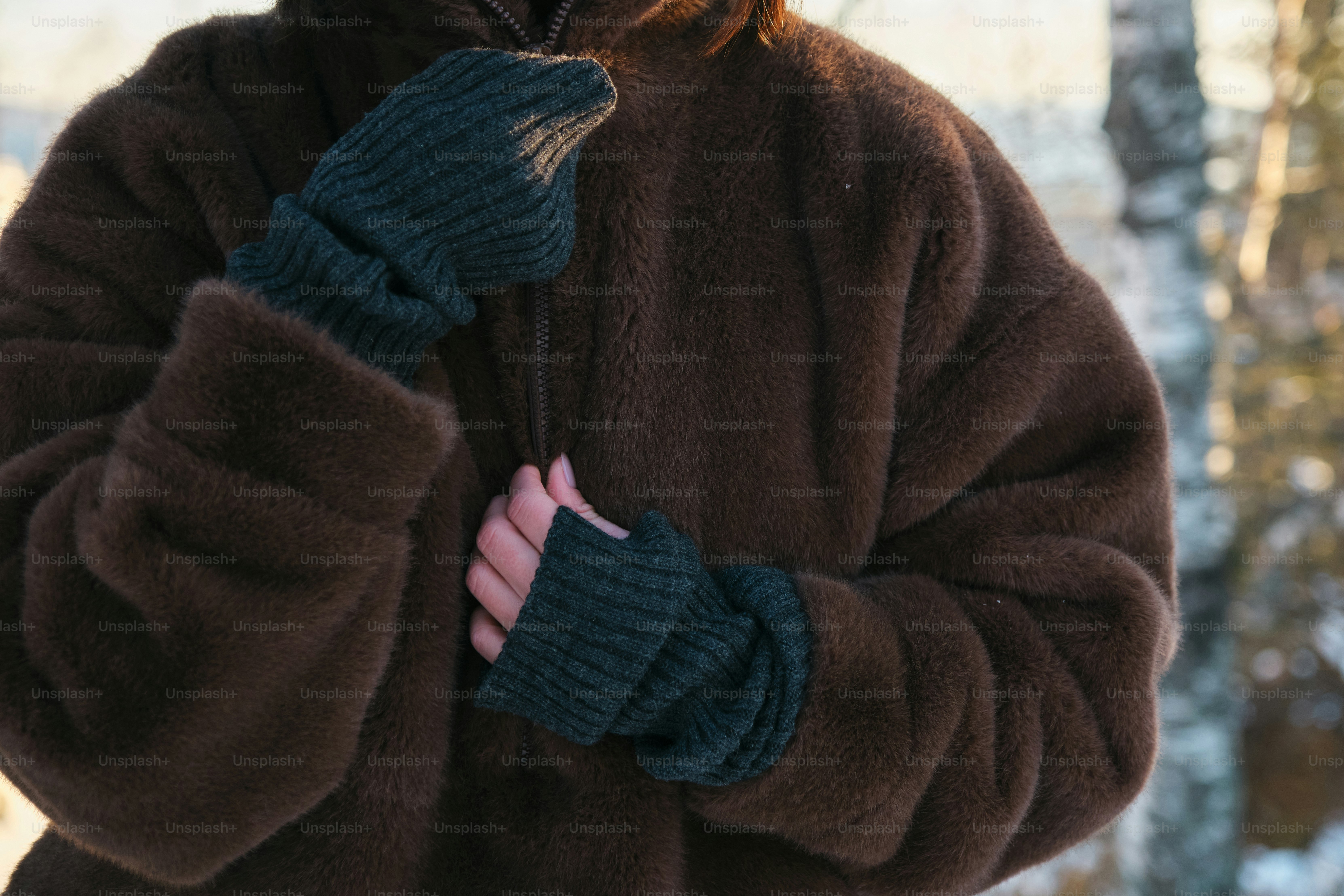 갈색 코트를 입고 눈 속에 서 있는 여자