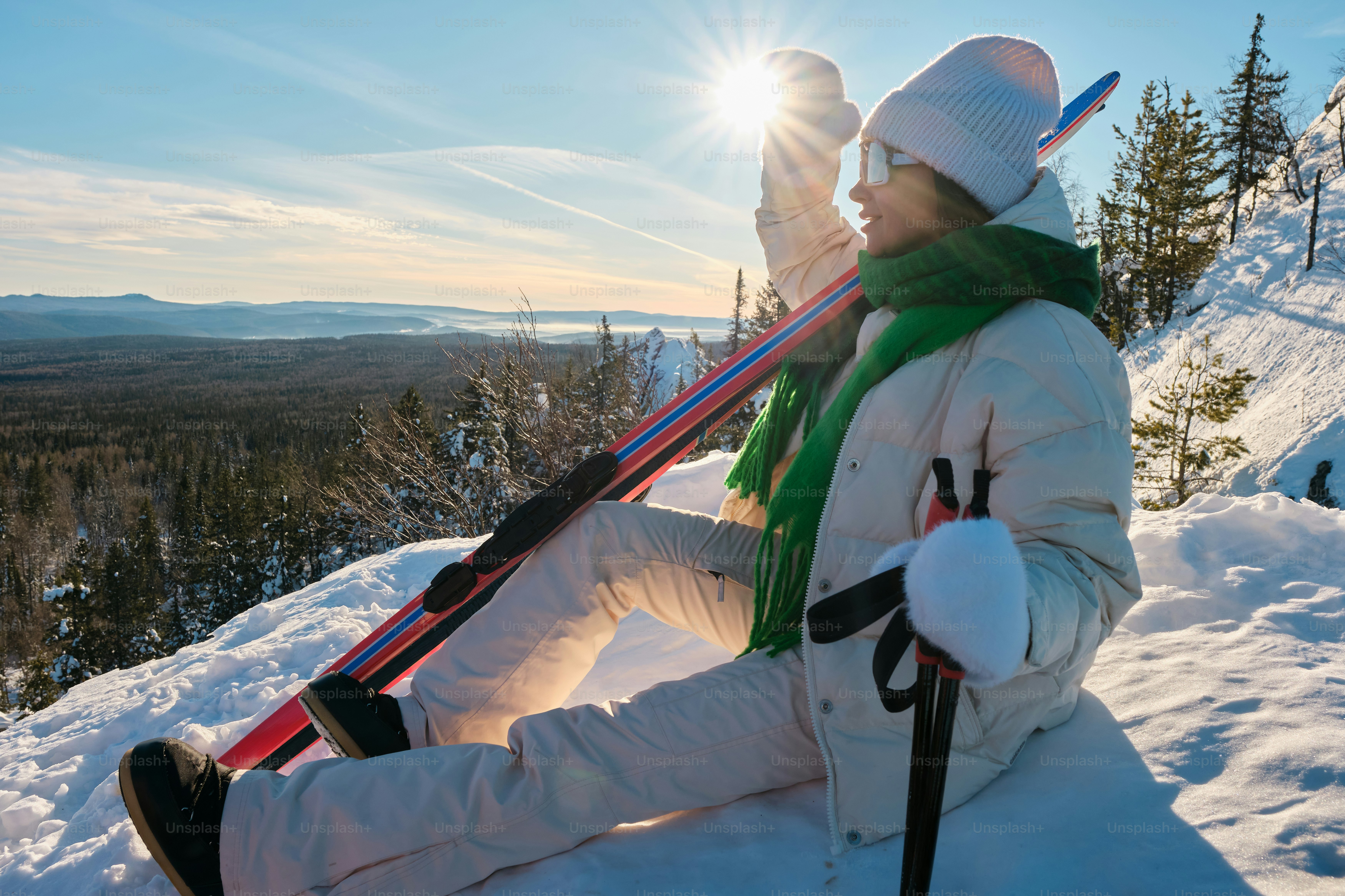 A person sitting in the snow with a pair of skis