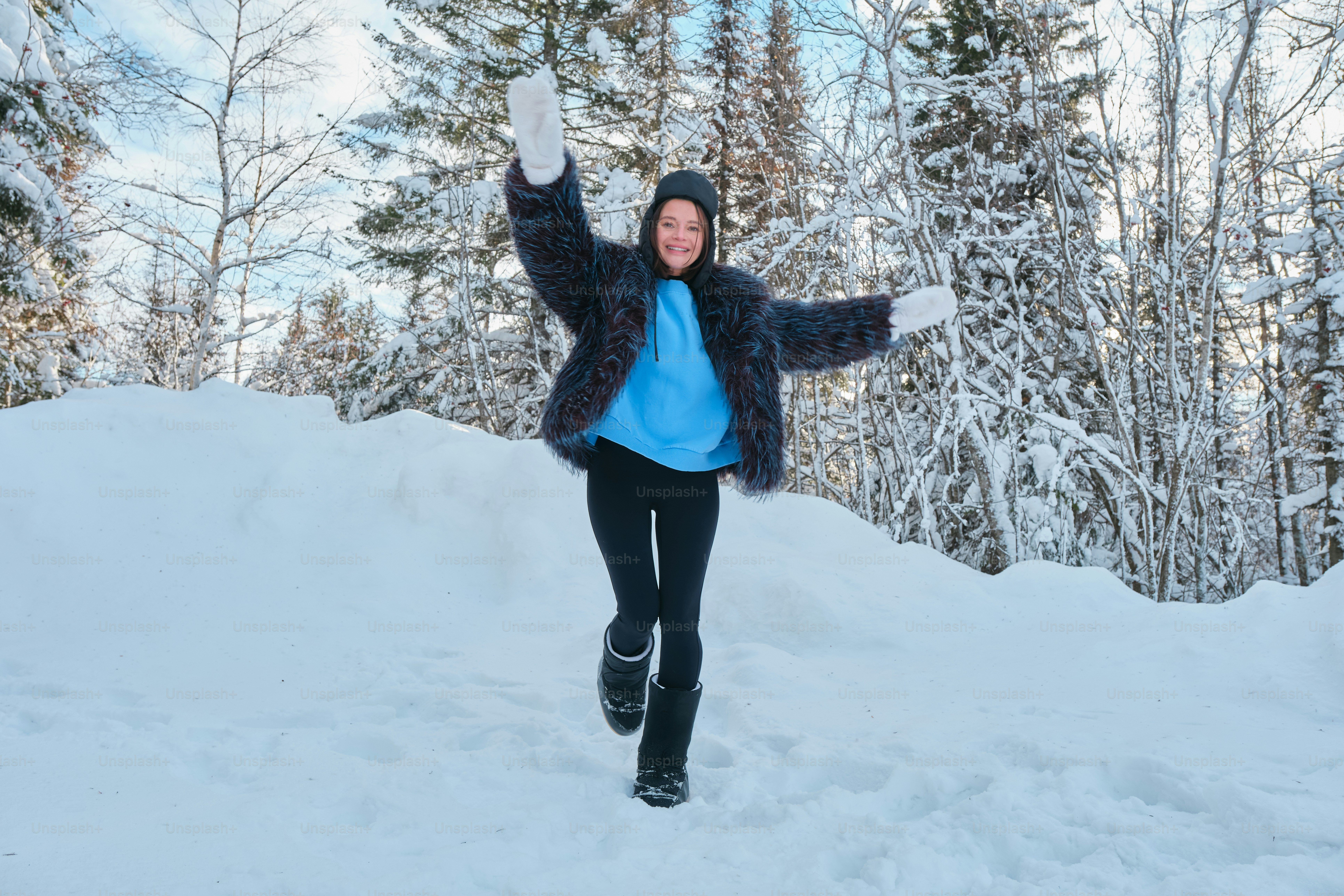 A woman walking through the snow with her arms in the air