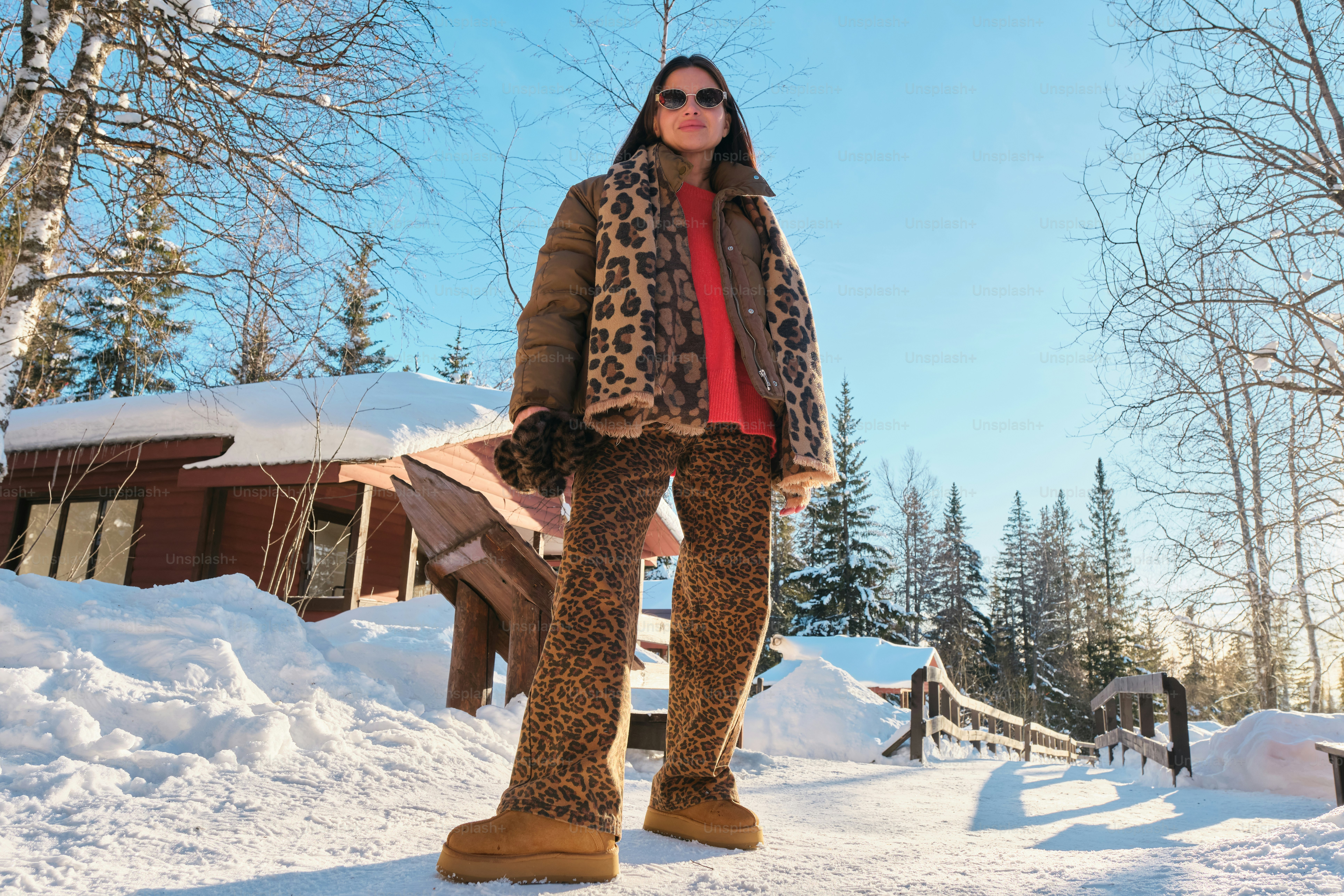 A woman standing in the snow wearing a leopard print coat