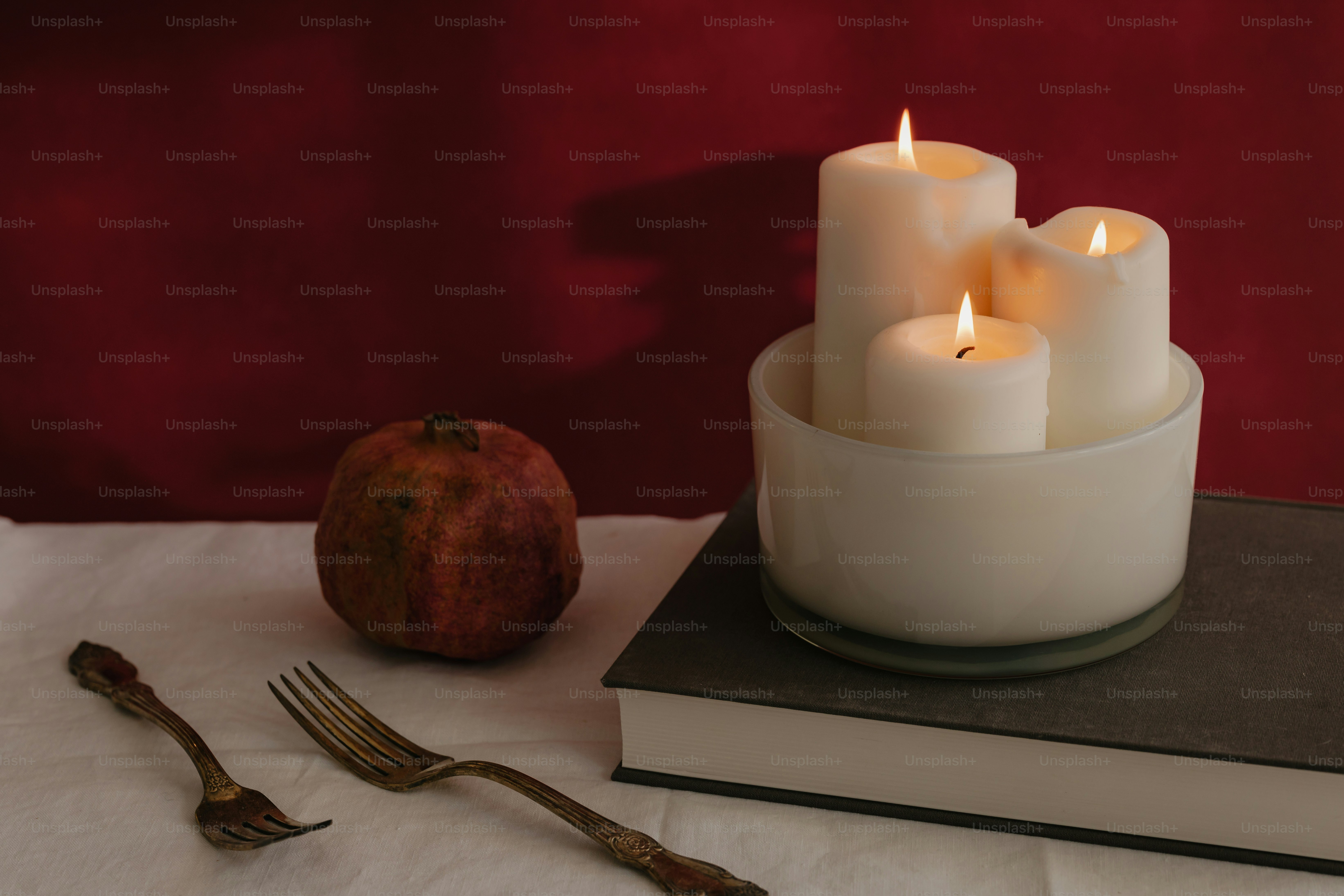 Un tavolo sormontato da una pila di libri accanto a una candela accesa