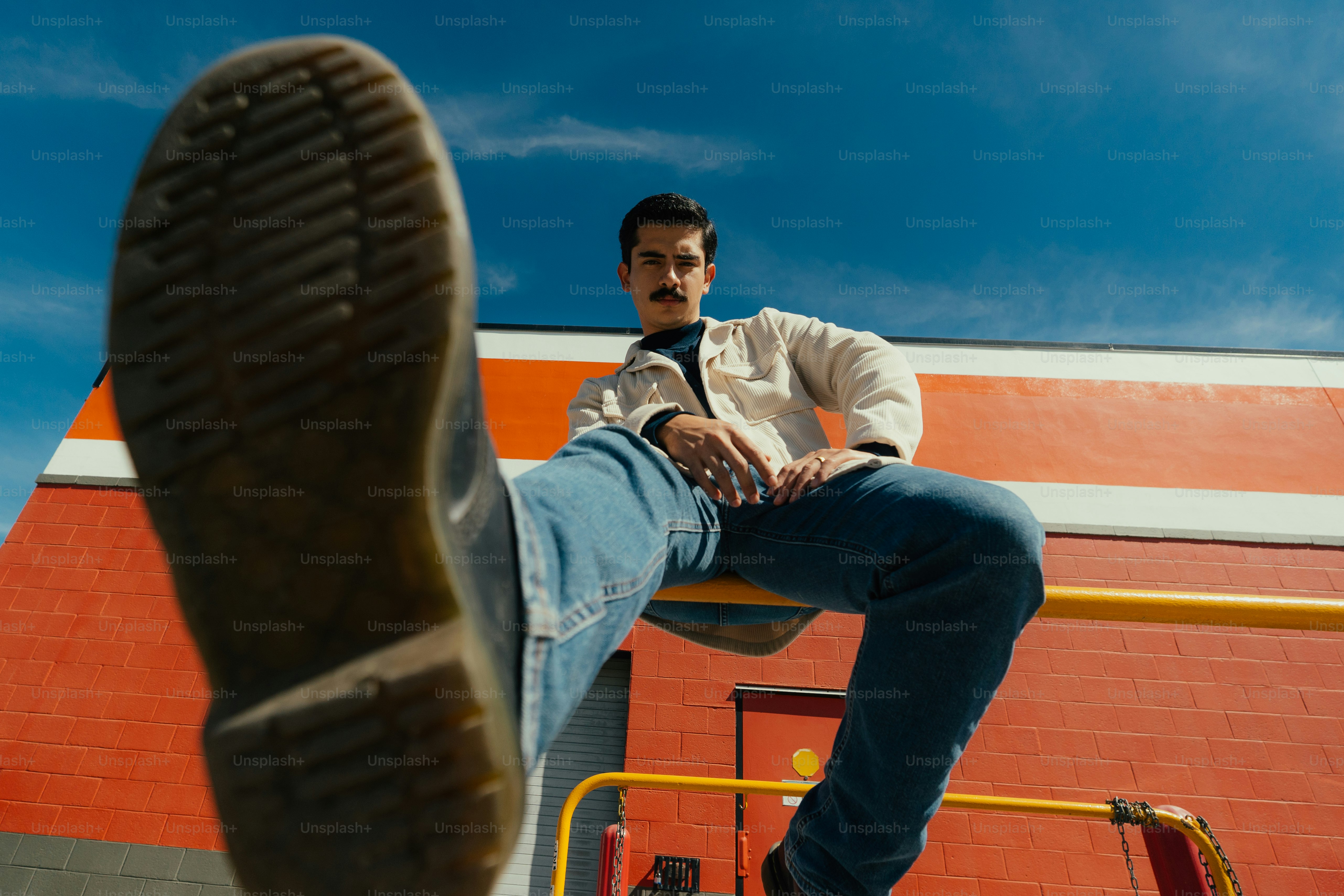 A man sitting on top of a metal rail next to a building