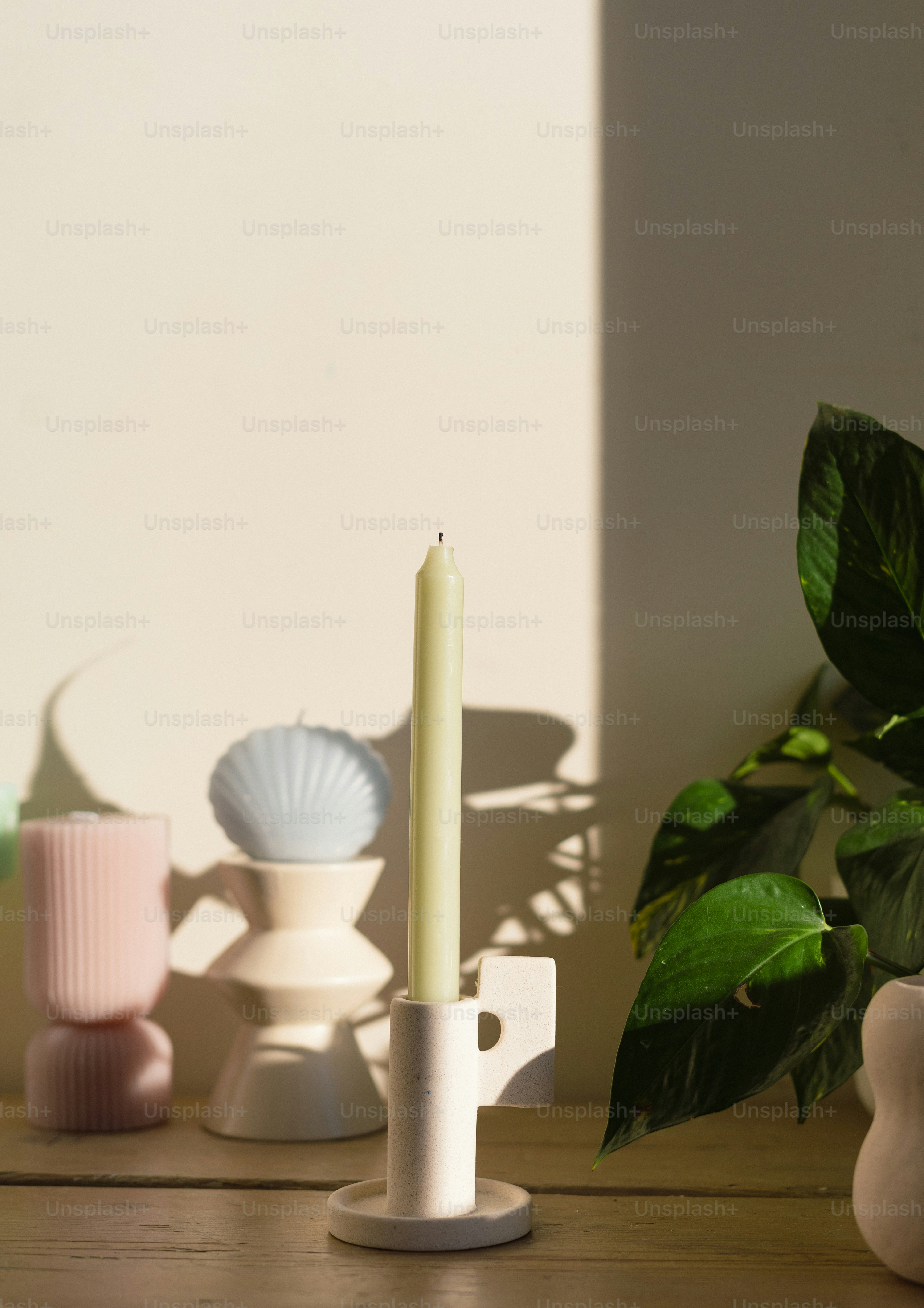 A candle is sitting on a table next to a potted plant