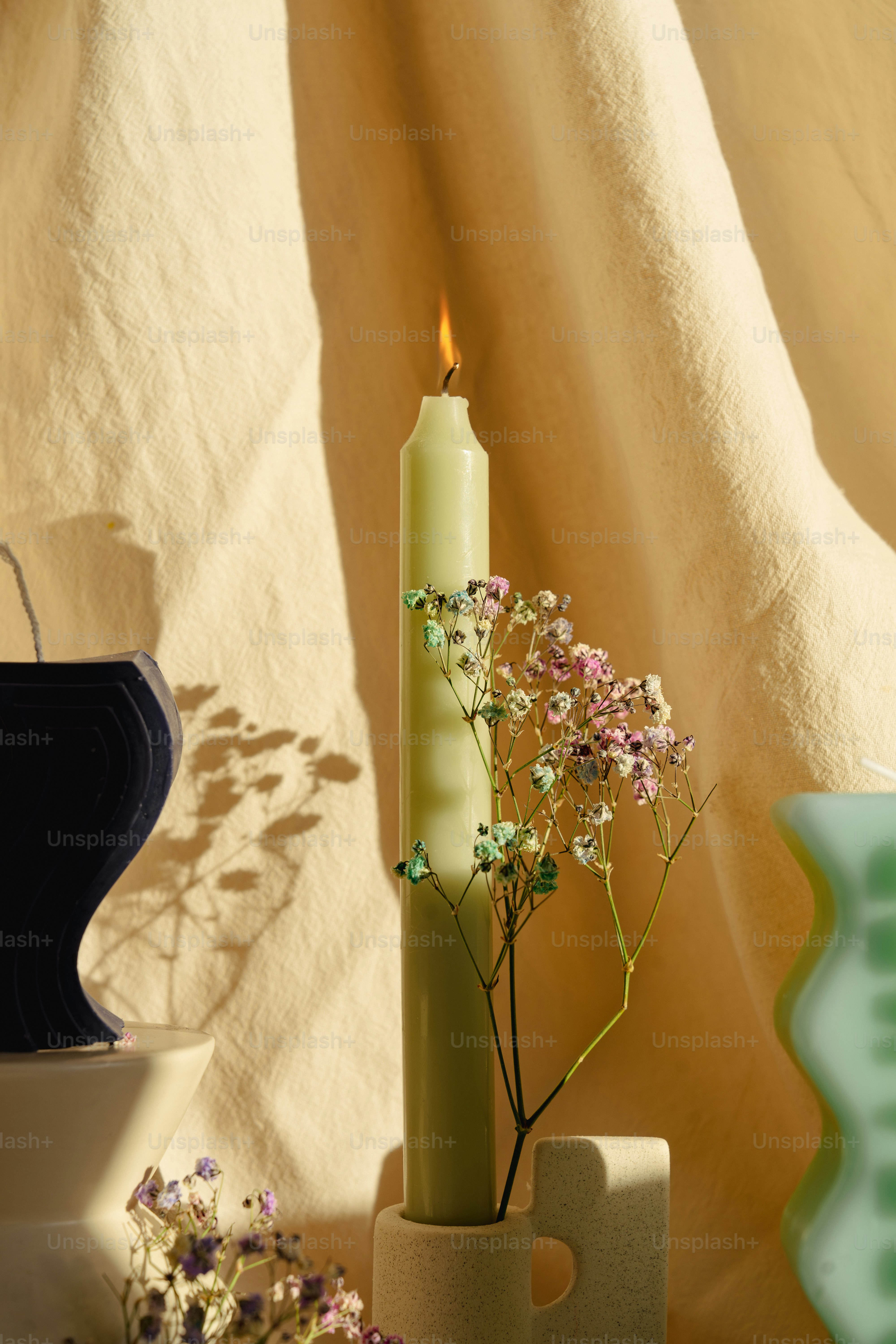 A vase with flowers and a candle on a table