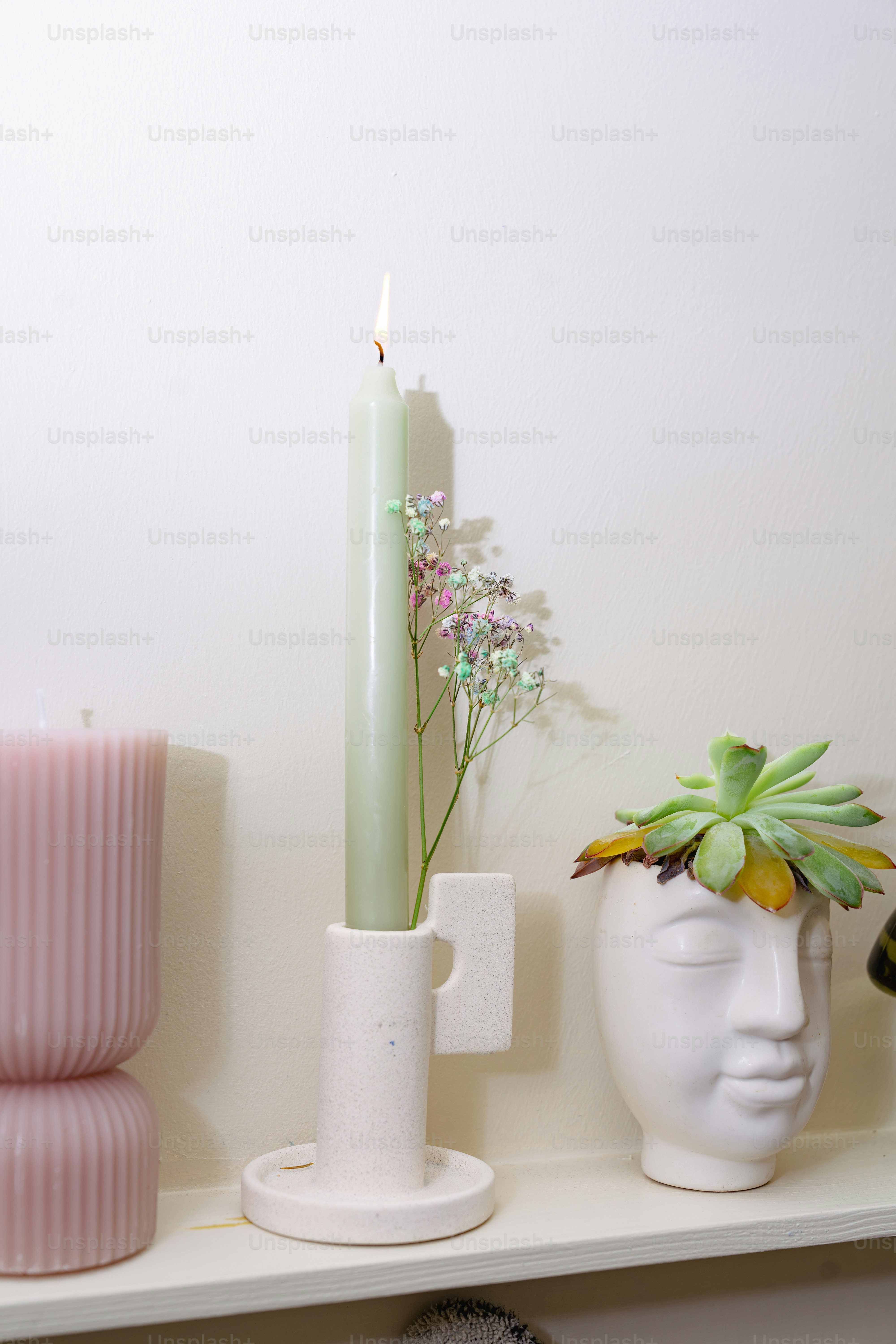 A white shelf topped with vases and a candle