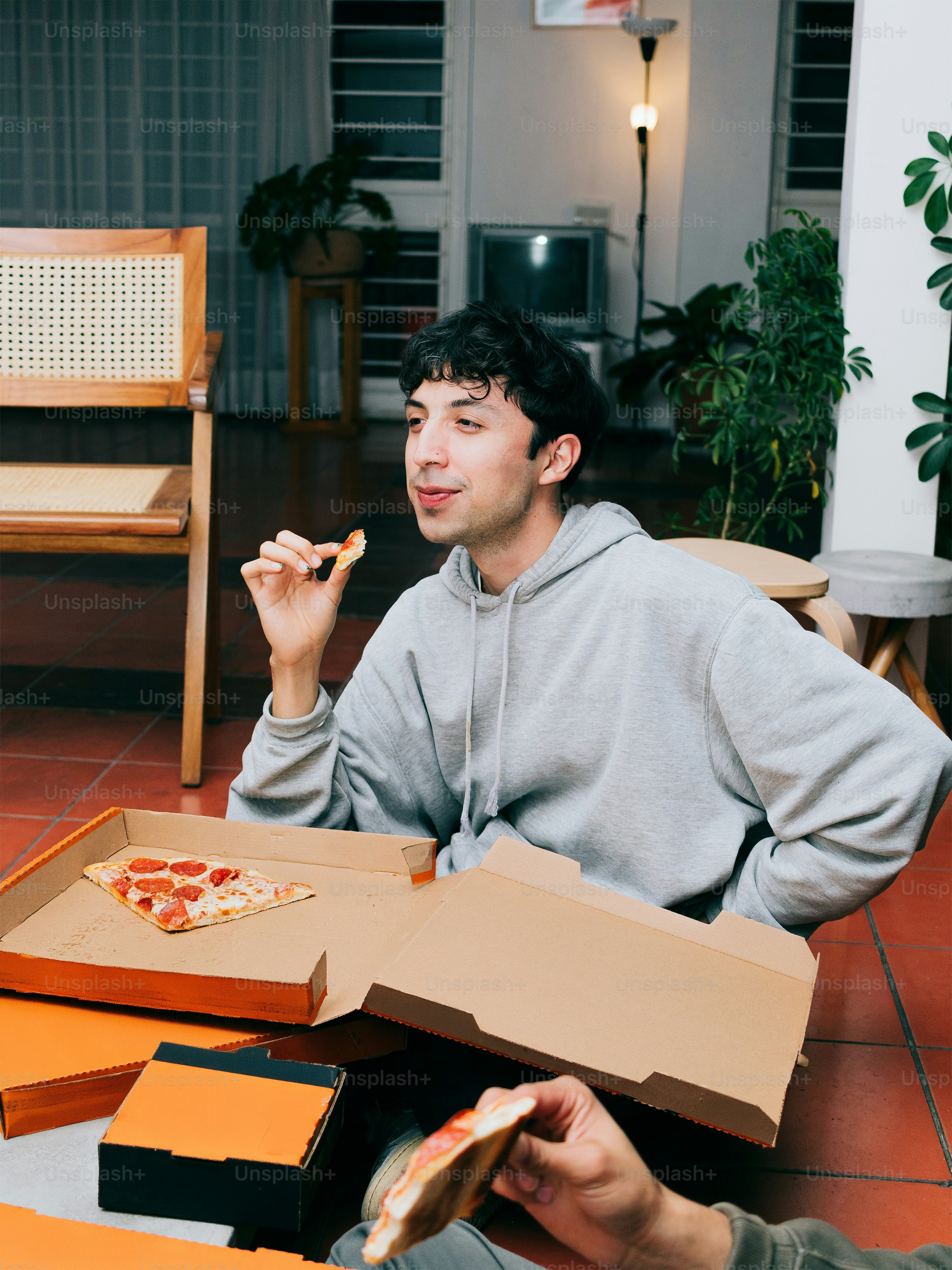 A man sitting on the floor eating pizza