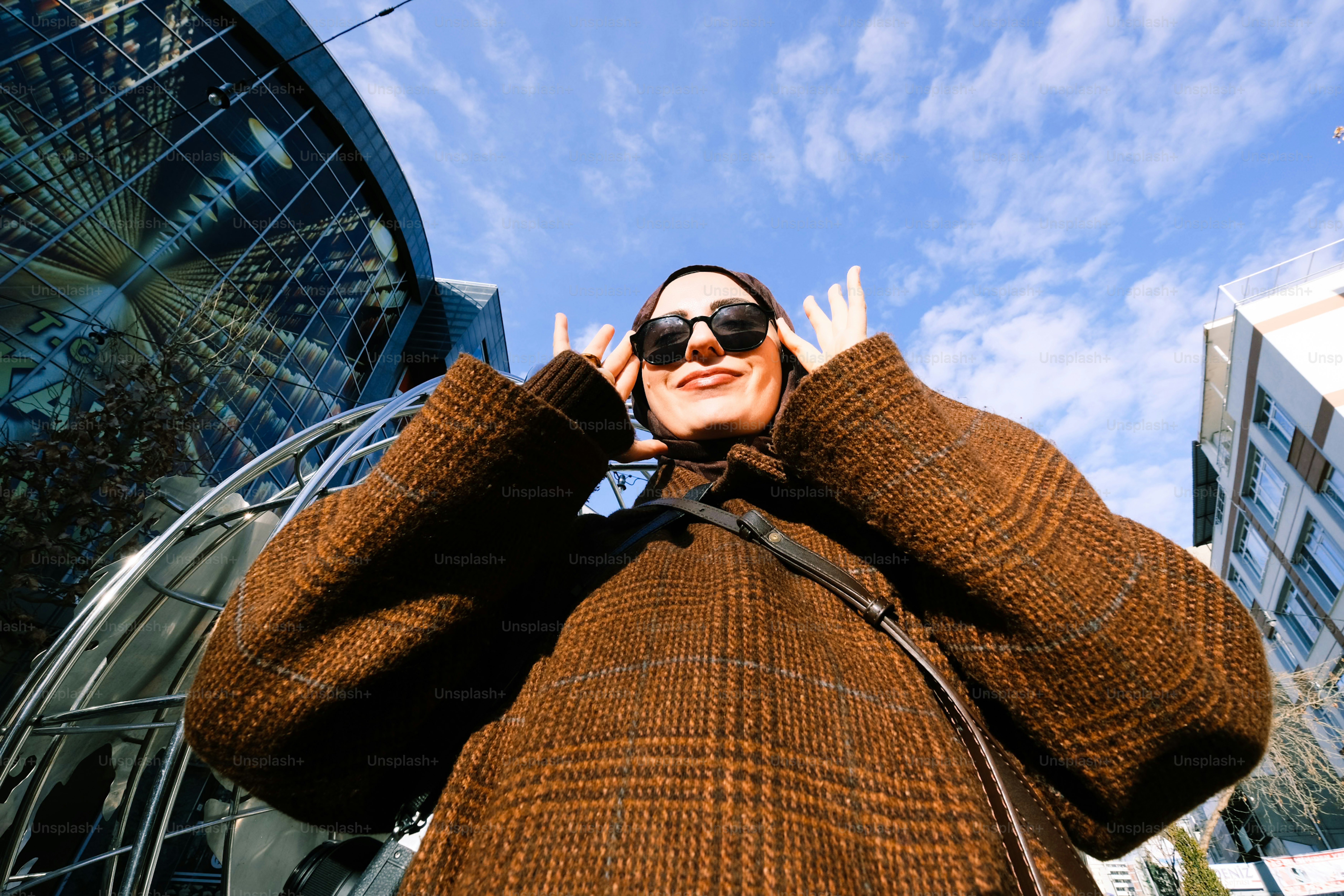 A woman in a brown sweater and sunglasses talking on a cell phone