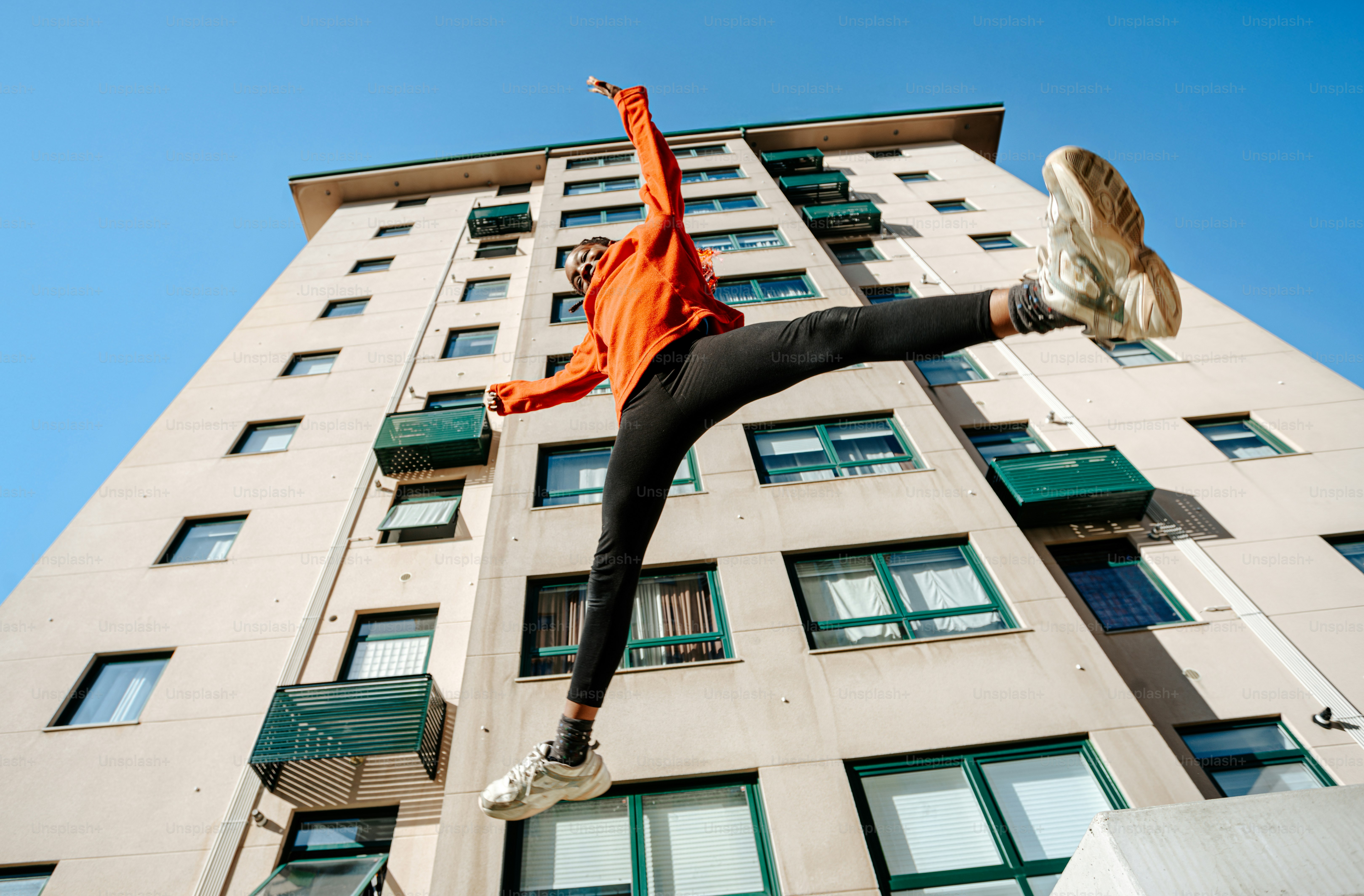 A woman is jumping in the air in front of a tall building