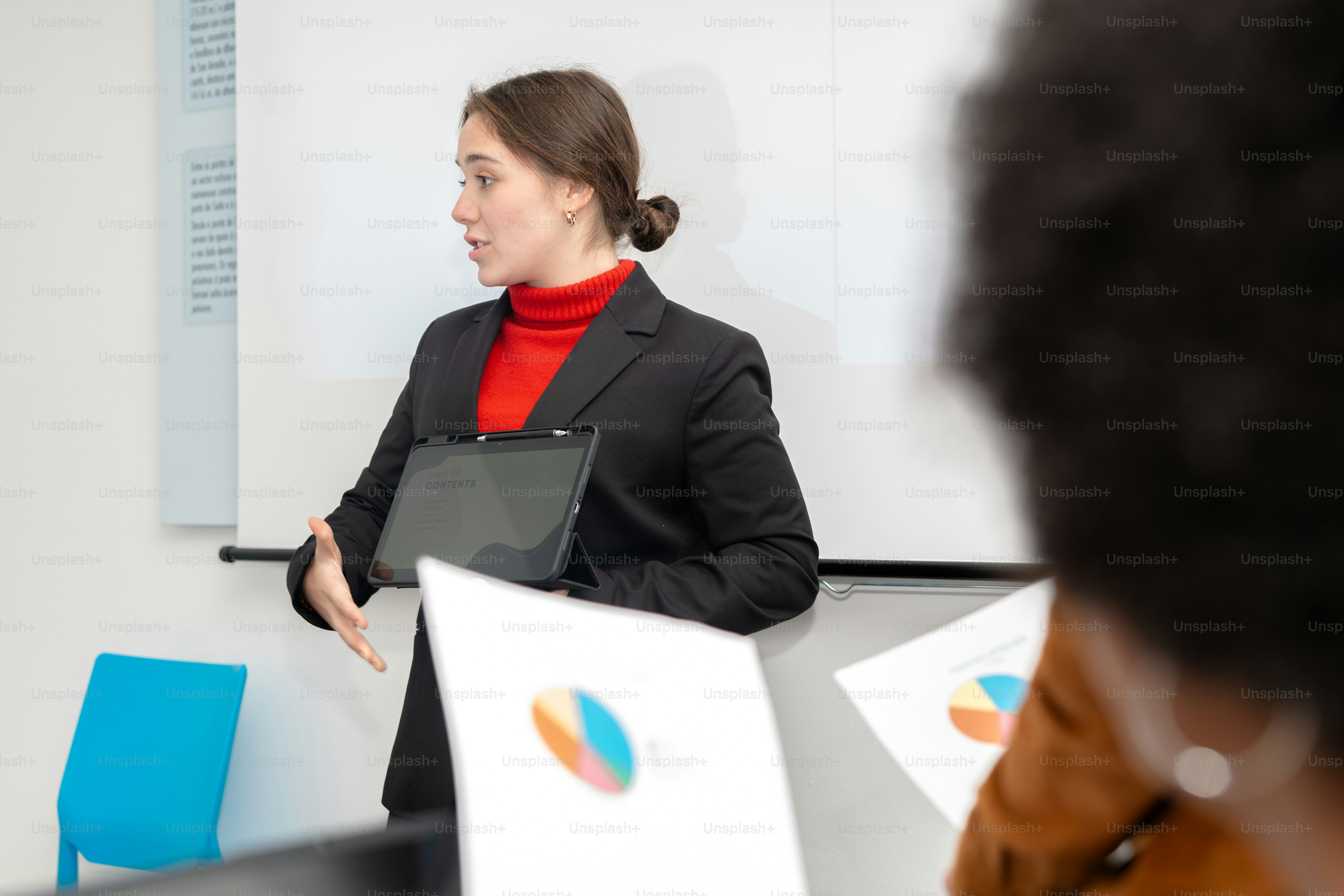 A woman standing in front of a whiteboard giving a presentation